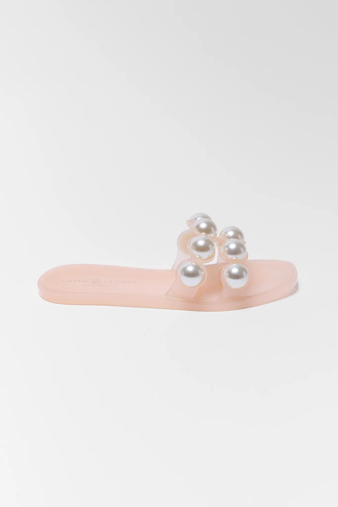 Pink sandal with pearl embellishments on a light gray background