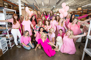 group photo of women wearing pink with pink balloons in warehouse