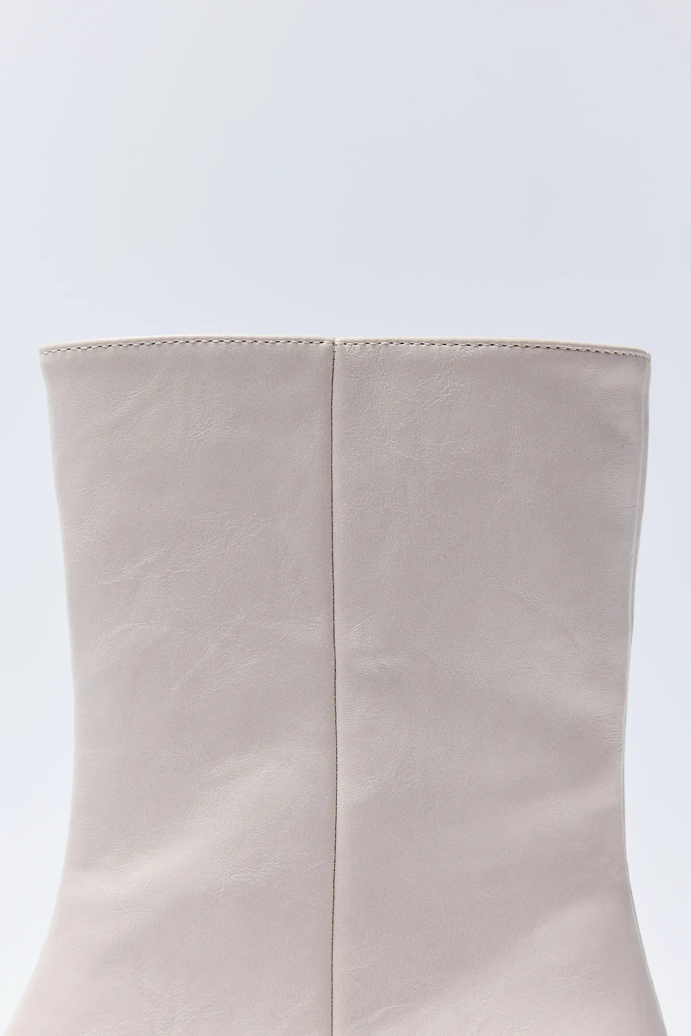 Close-up of a beige Adler Boots on a light blue background