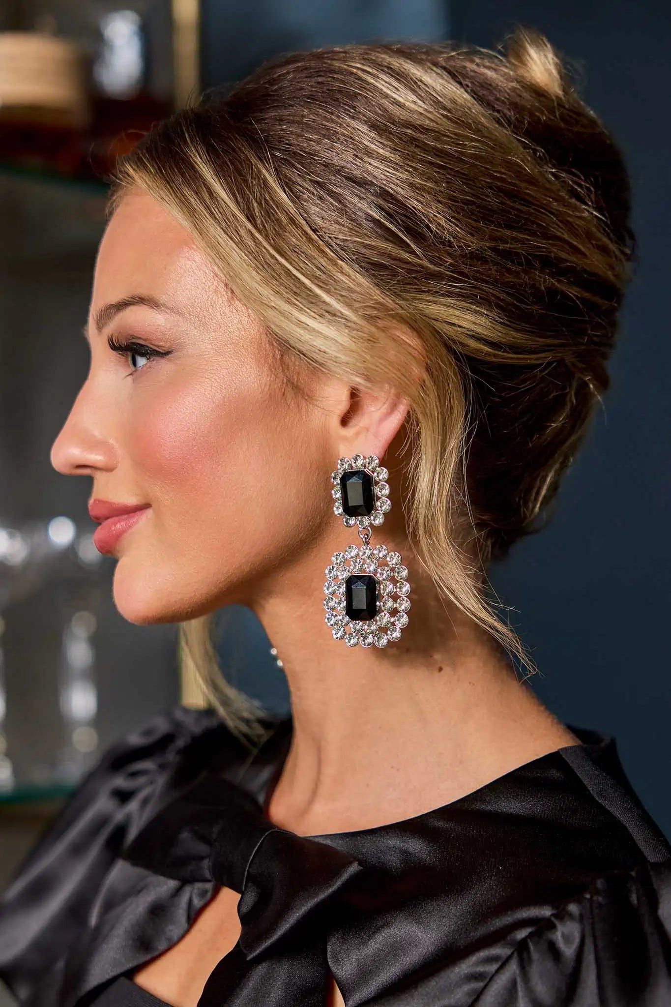 Woman wearing large black and silver earrings with a blurred background