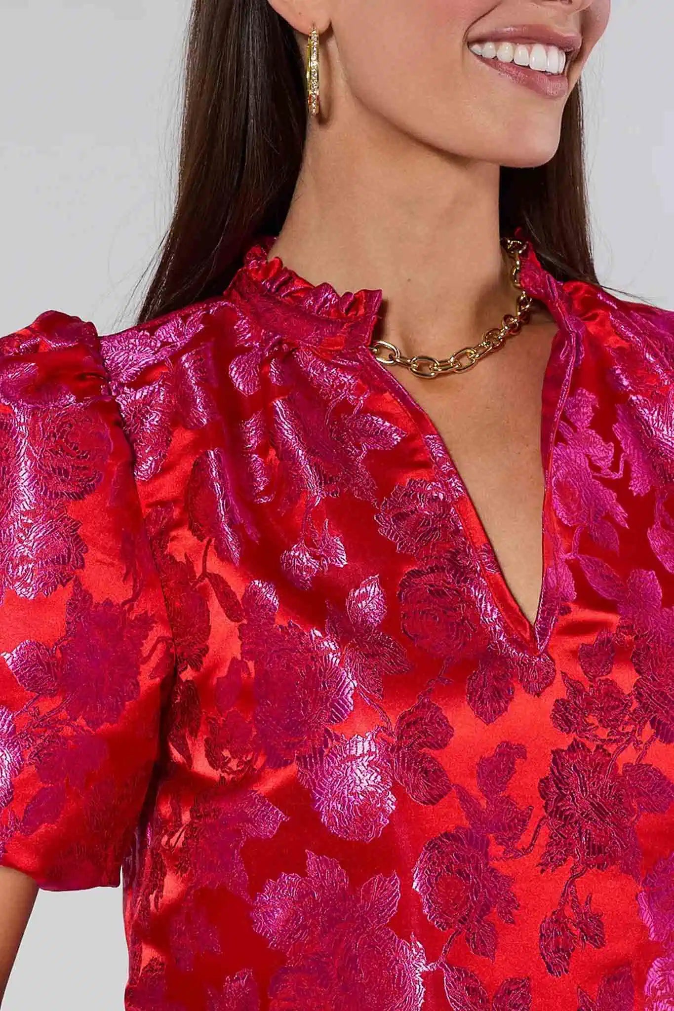 Woman wearing a red Alyssa Brocade Puff Sleeve Top against a gray background