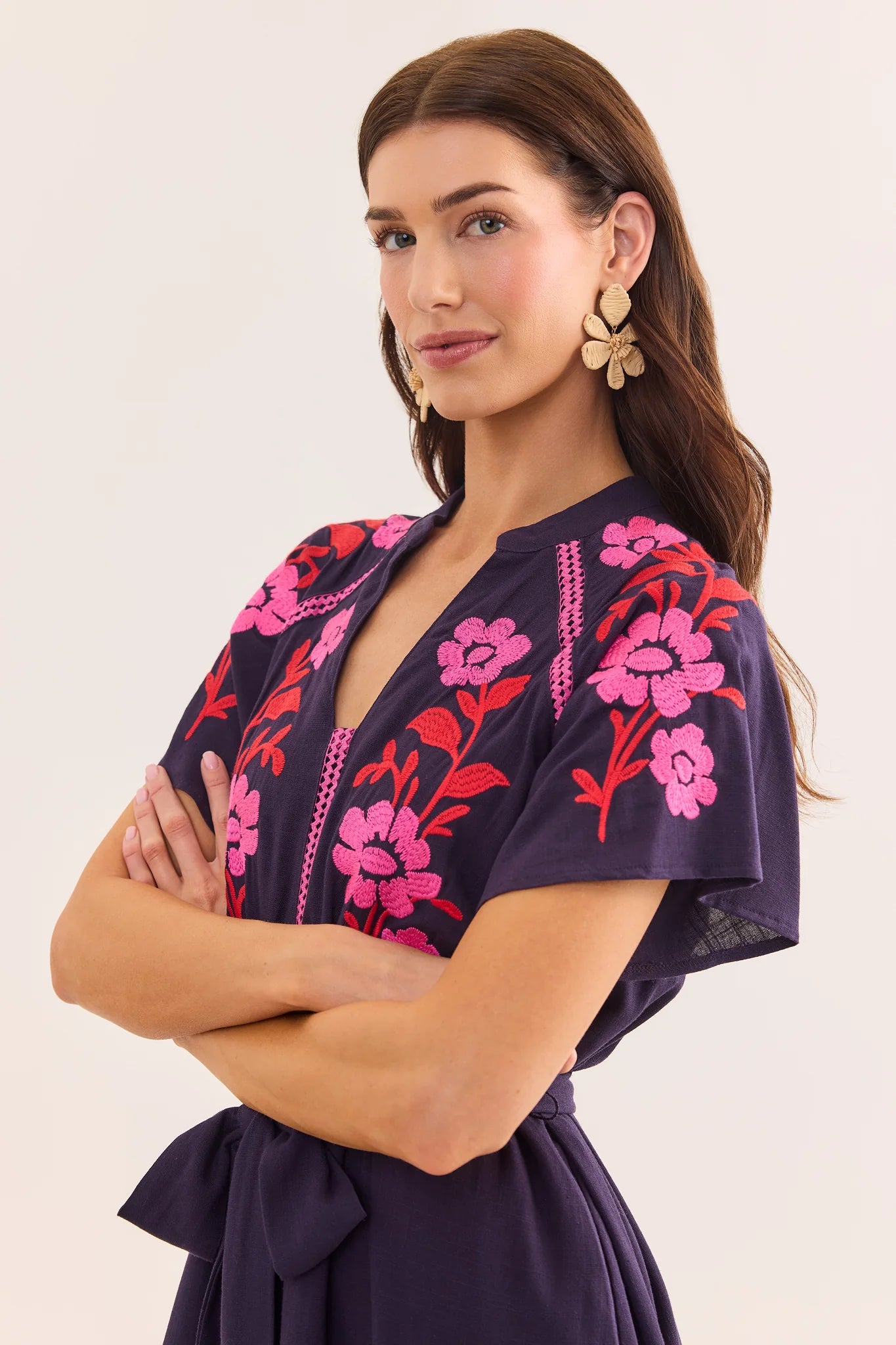Woman wearing a dark purple dress with pink floral embroidery on a white background lifestyle