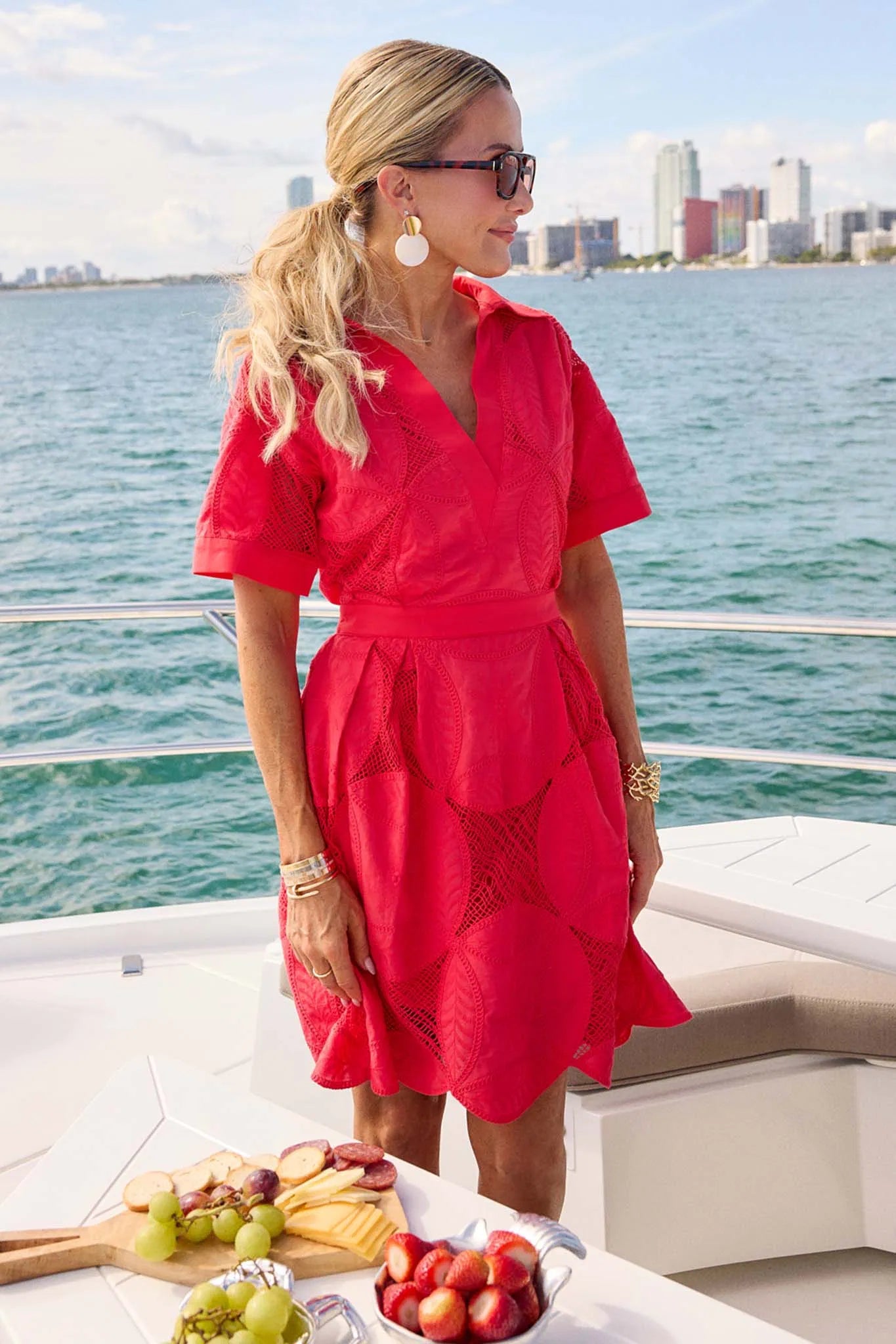 Woman in a red dress on a boat with a city skyline in the background