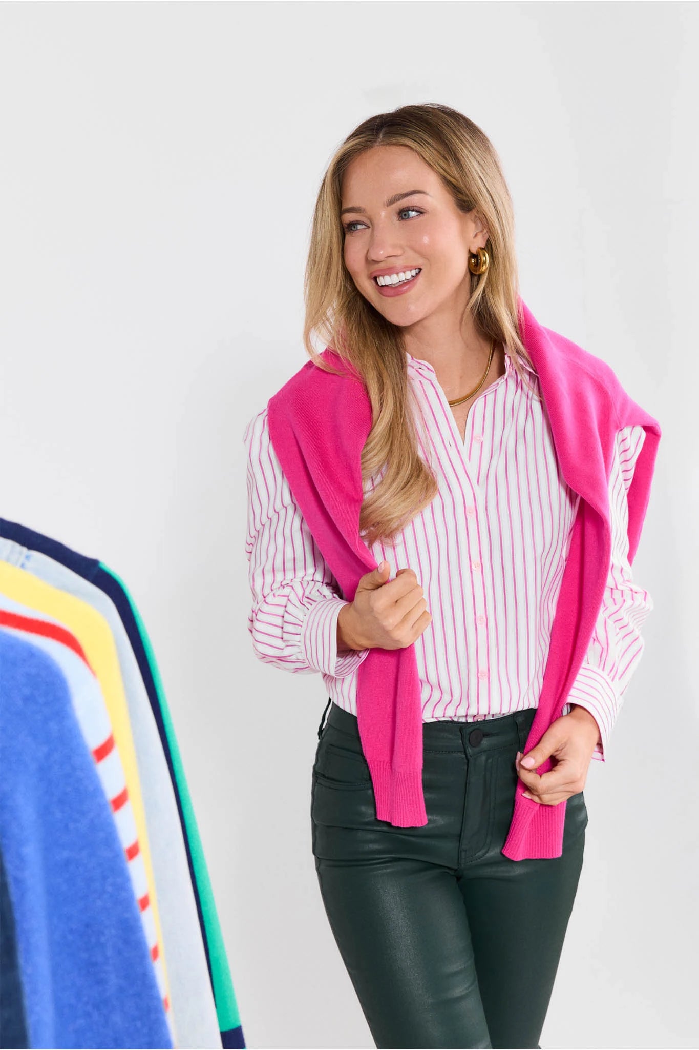 Woman wearing a pink cardigan over a striped shirt with a white background