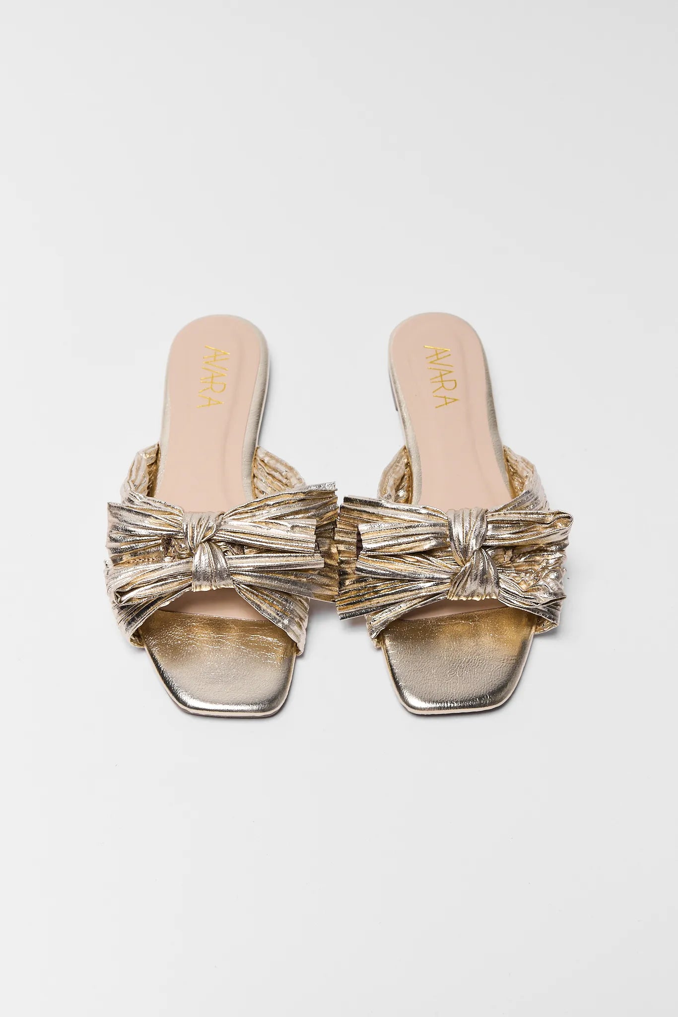 Gold sandals with bows on a light gray background