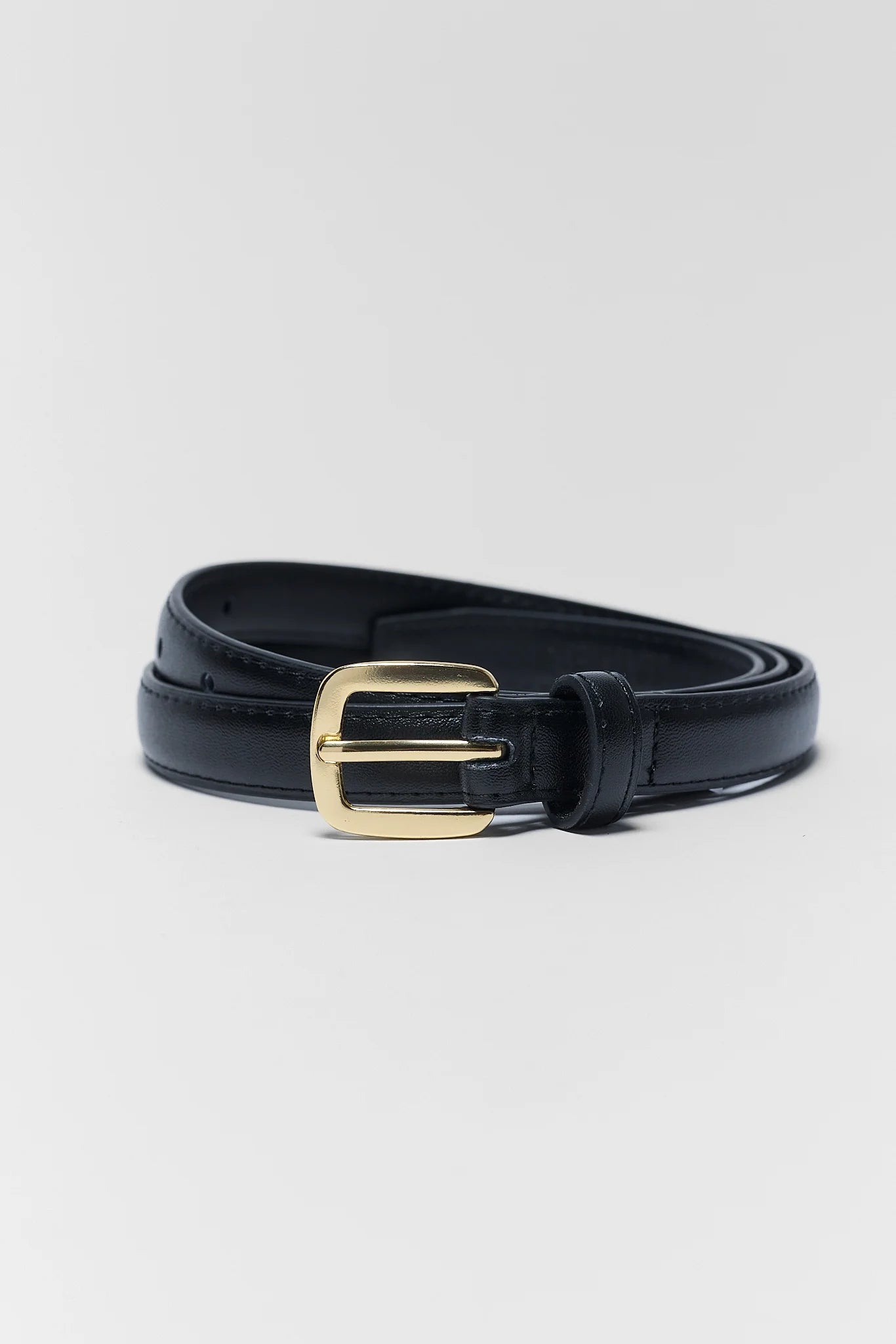 A black leather belt with a polished gold-tone buckle, neatly coiled on a light gray background.