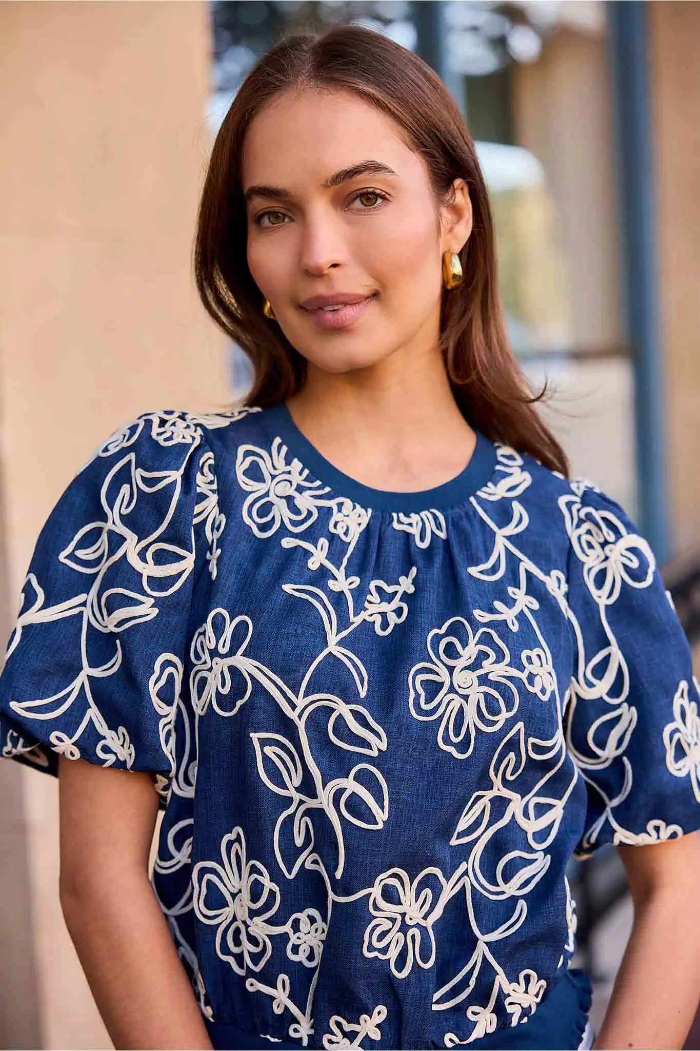 woman wearing navy embroidered top outside