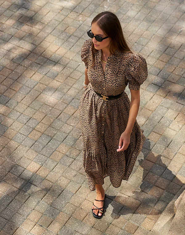 Woman in a leopard print Martha dress standing on a paved walkway