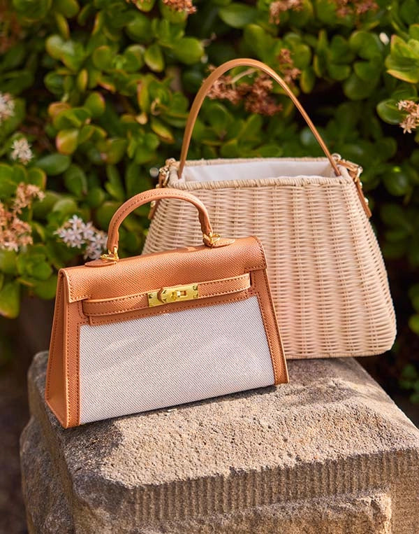 Handbag with a wicker basket on a stone surface with greenery in the background