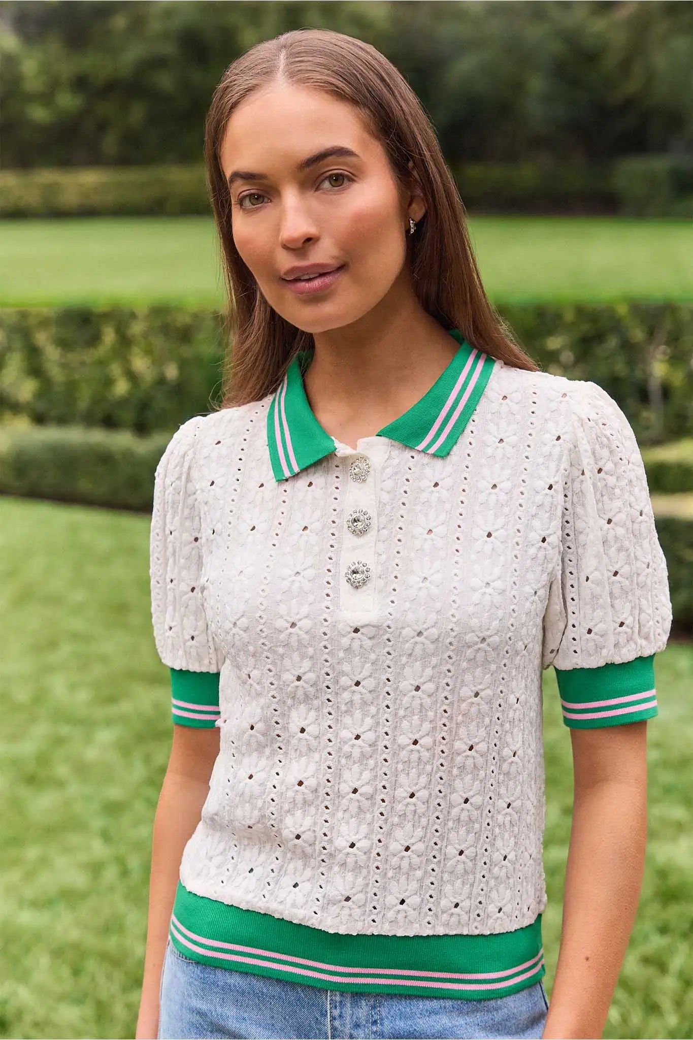 Woman wearing a white blouse with green accents in an outdoor setting