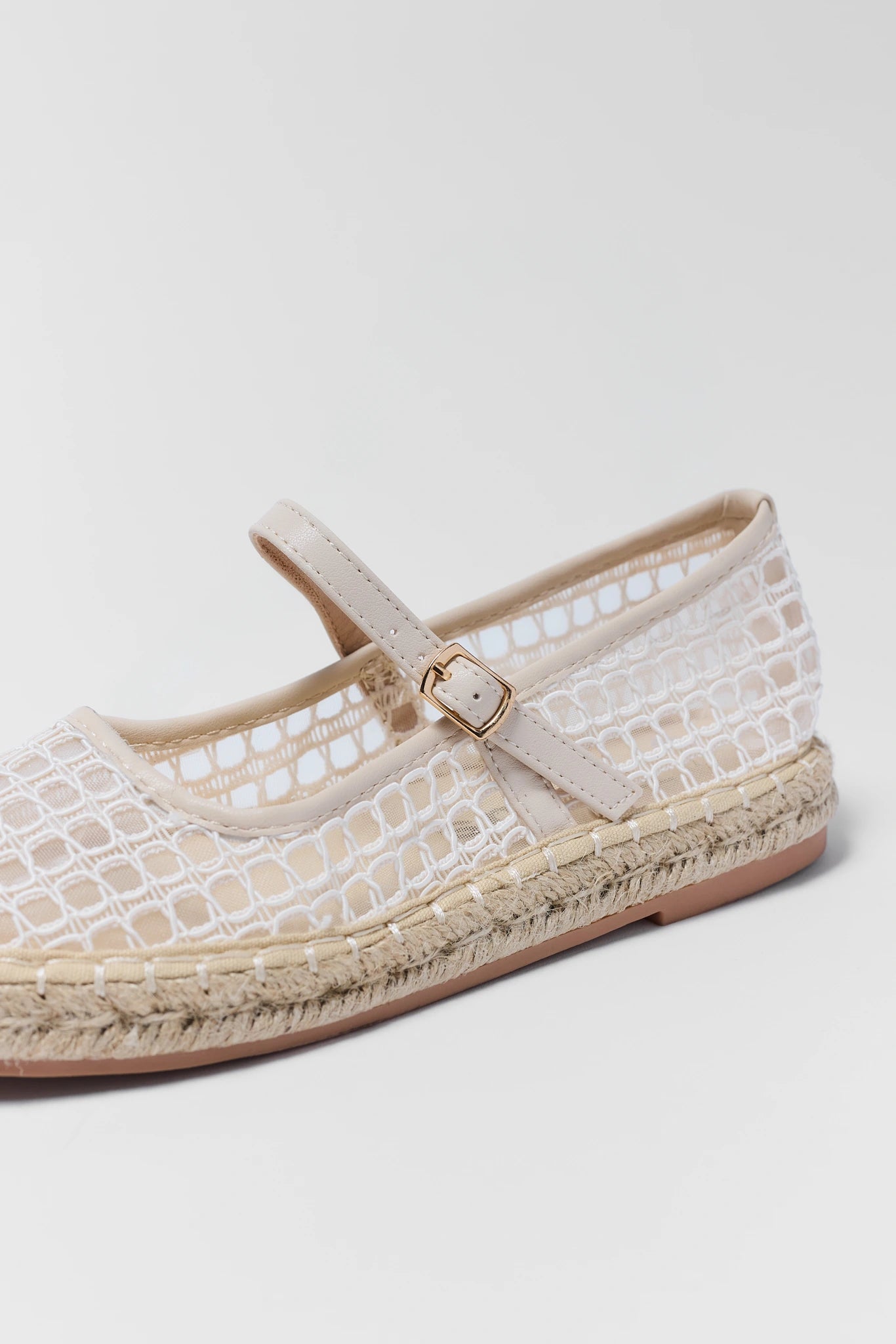 close up White lace espadrille shoe with a strap on a light gray background
