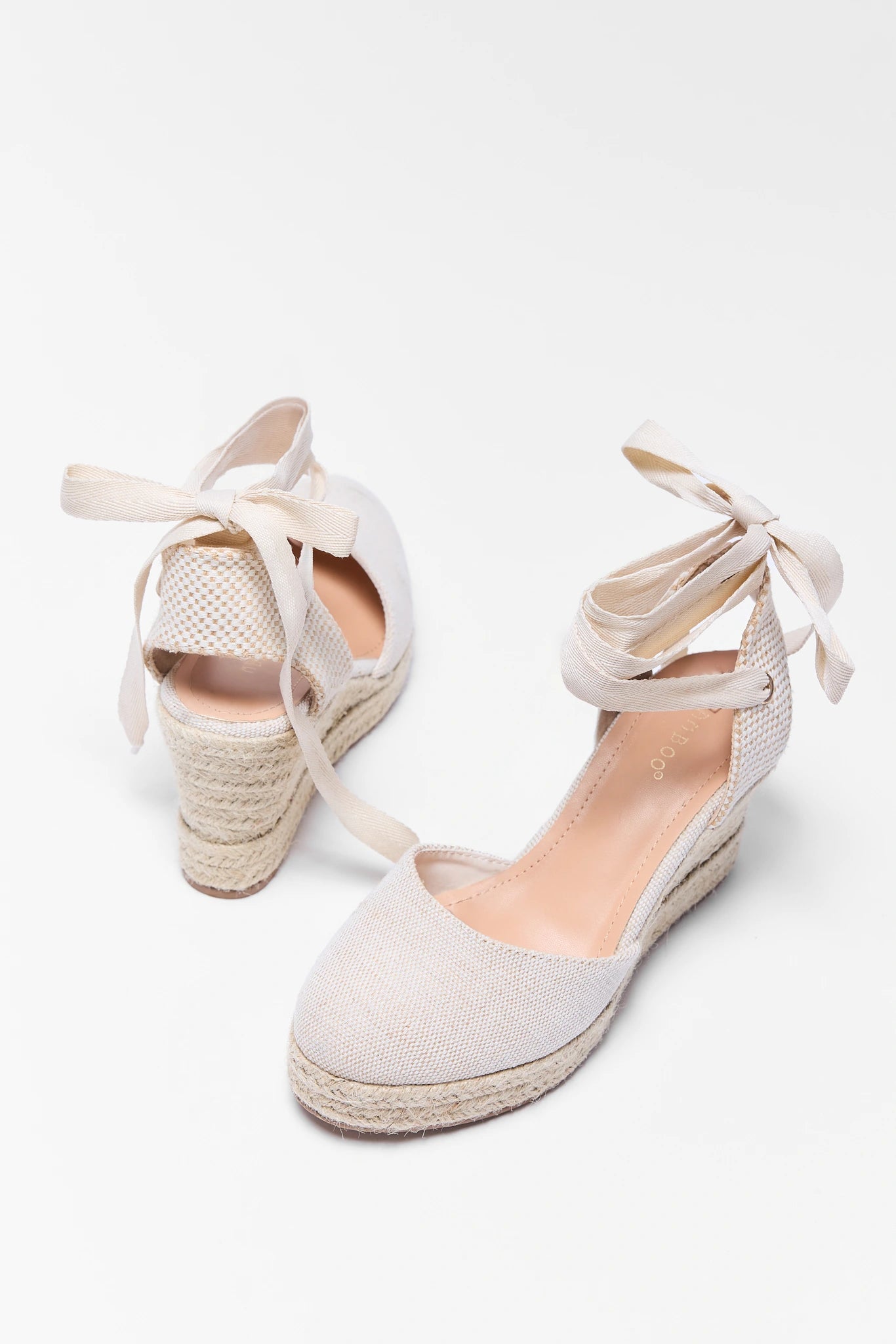 Pair of light gray wedge sandals with espadrille sole on a white background