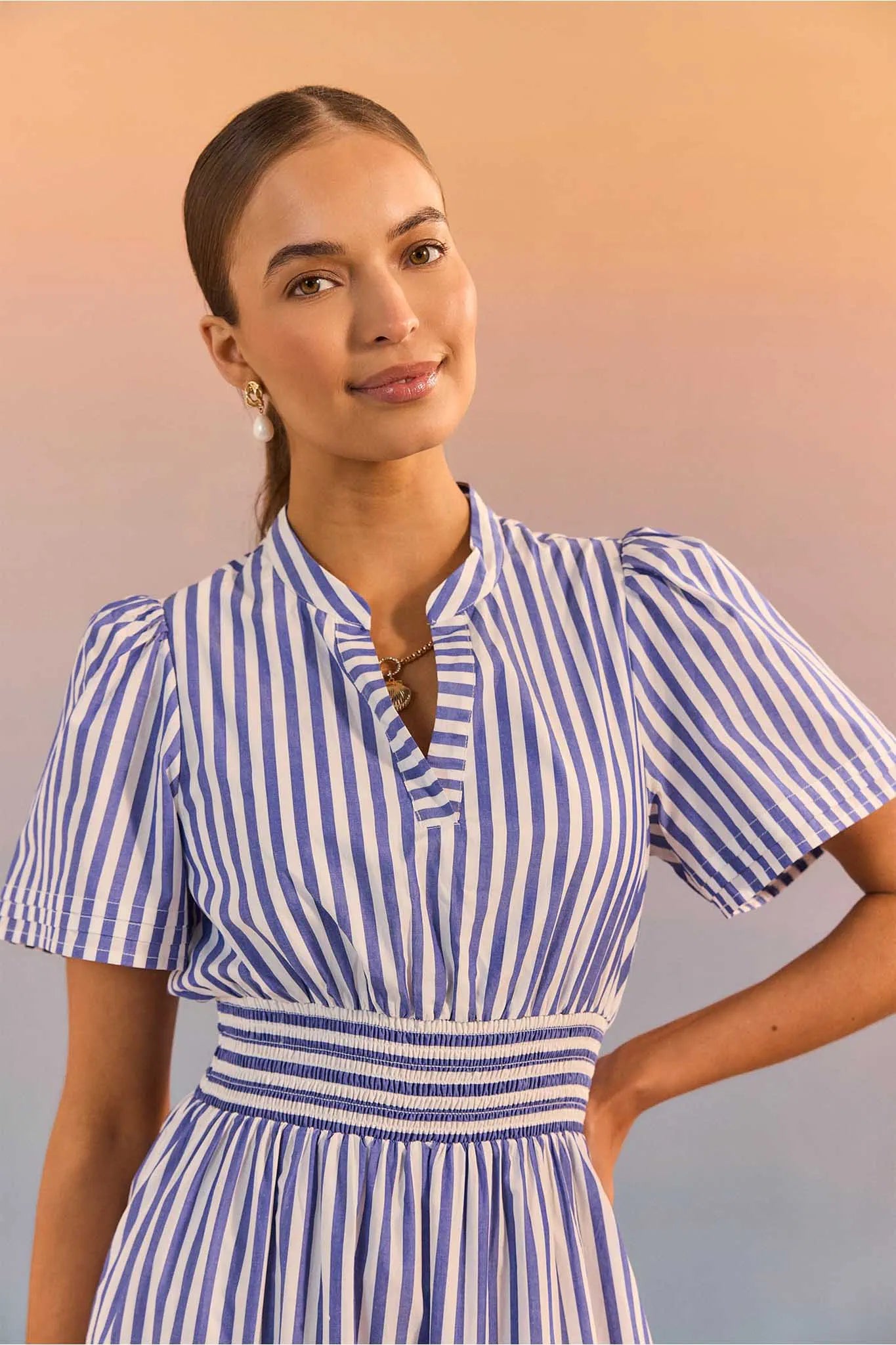 Woman wearing a blue and white striped dress against a gradient background