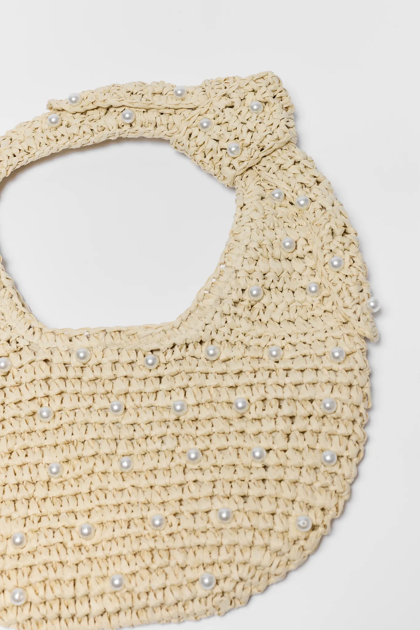 Beige woven bag with pearl embellishments on a light gray background