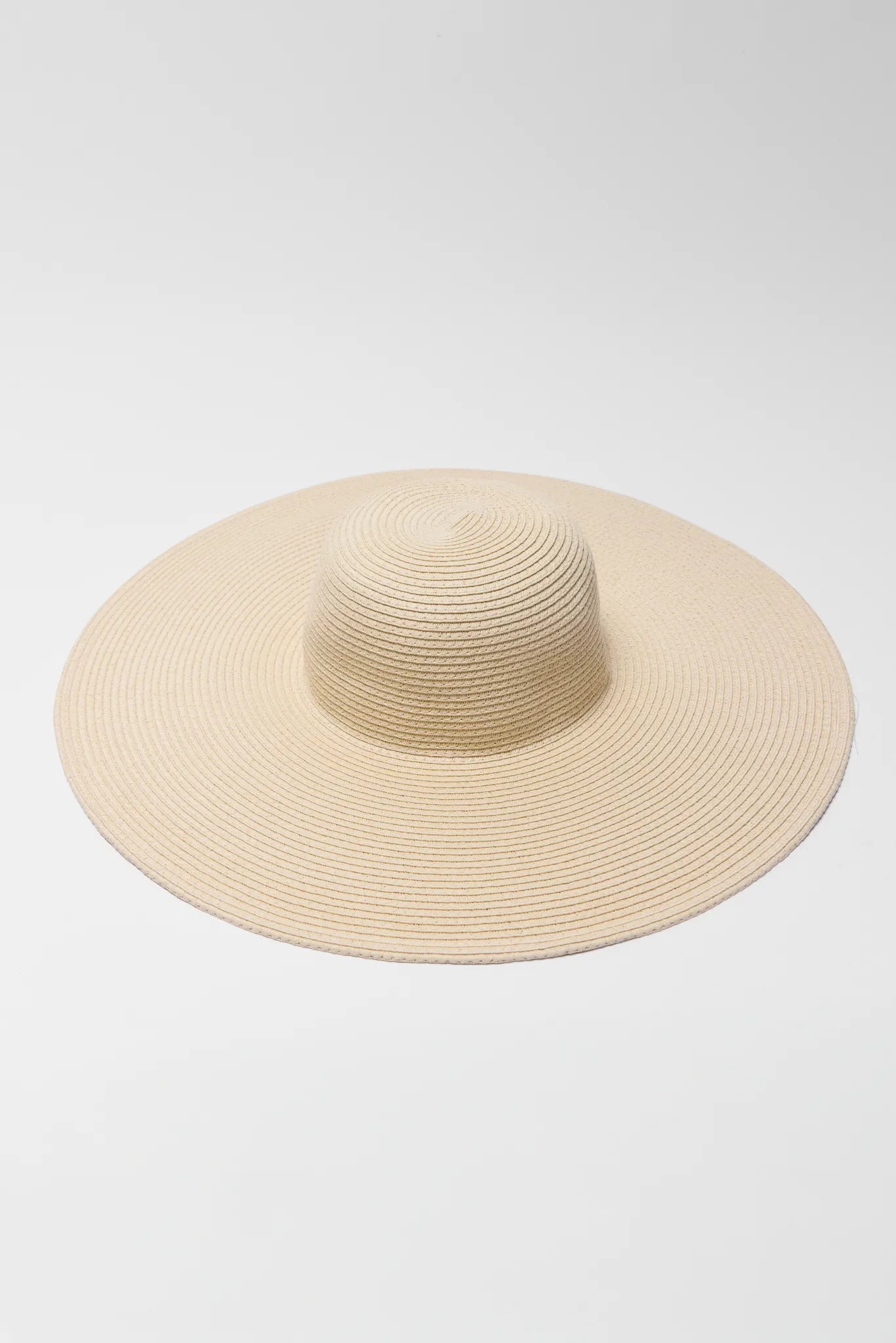 Betty Raffia Wide Brim Sun Hat features a woven straw finish with a floppy brim and round crown, perfect for sunny outings and vacations.