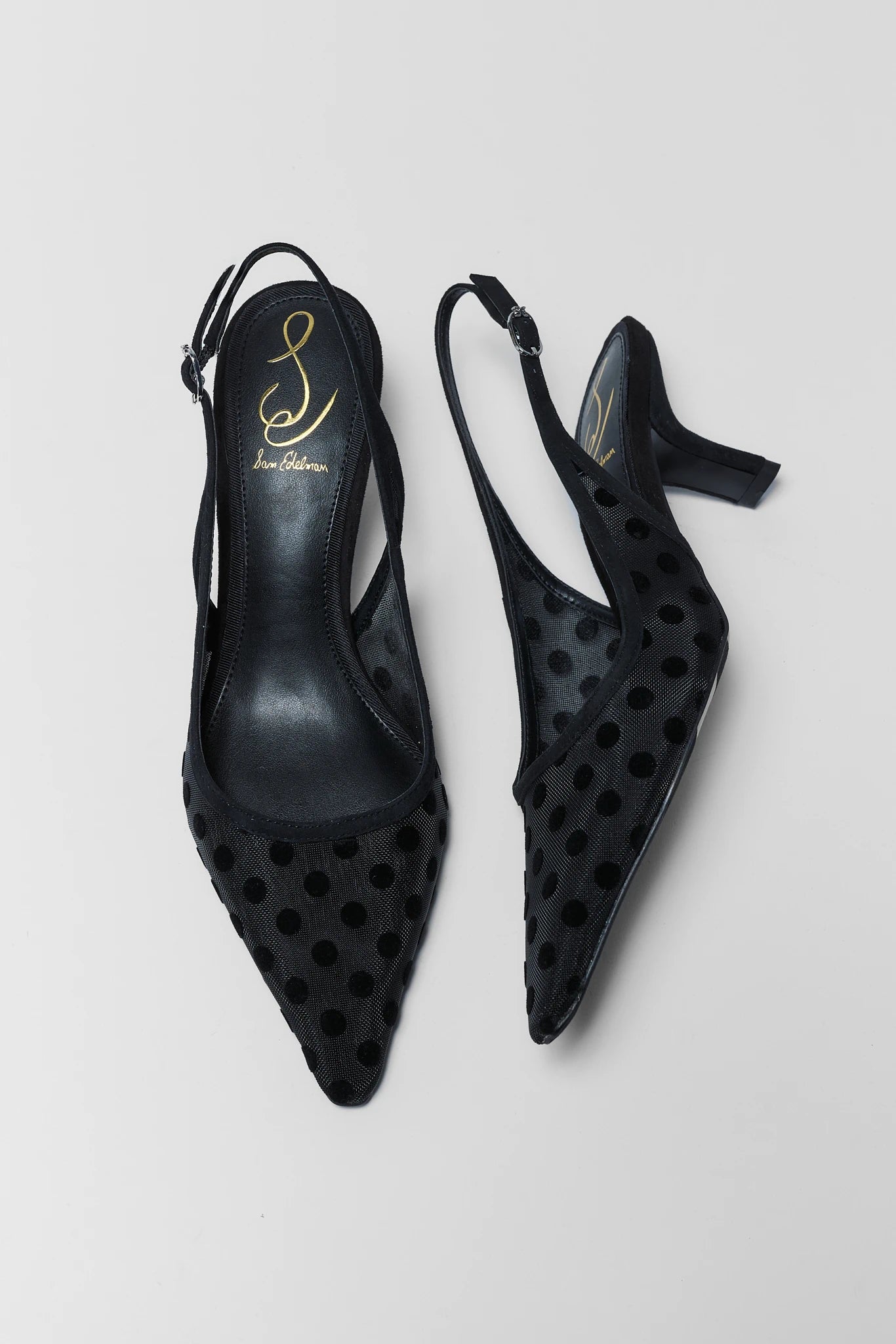 Black perforated high-heeled shoes on a light gray background