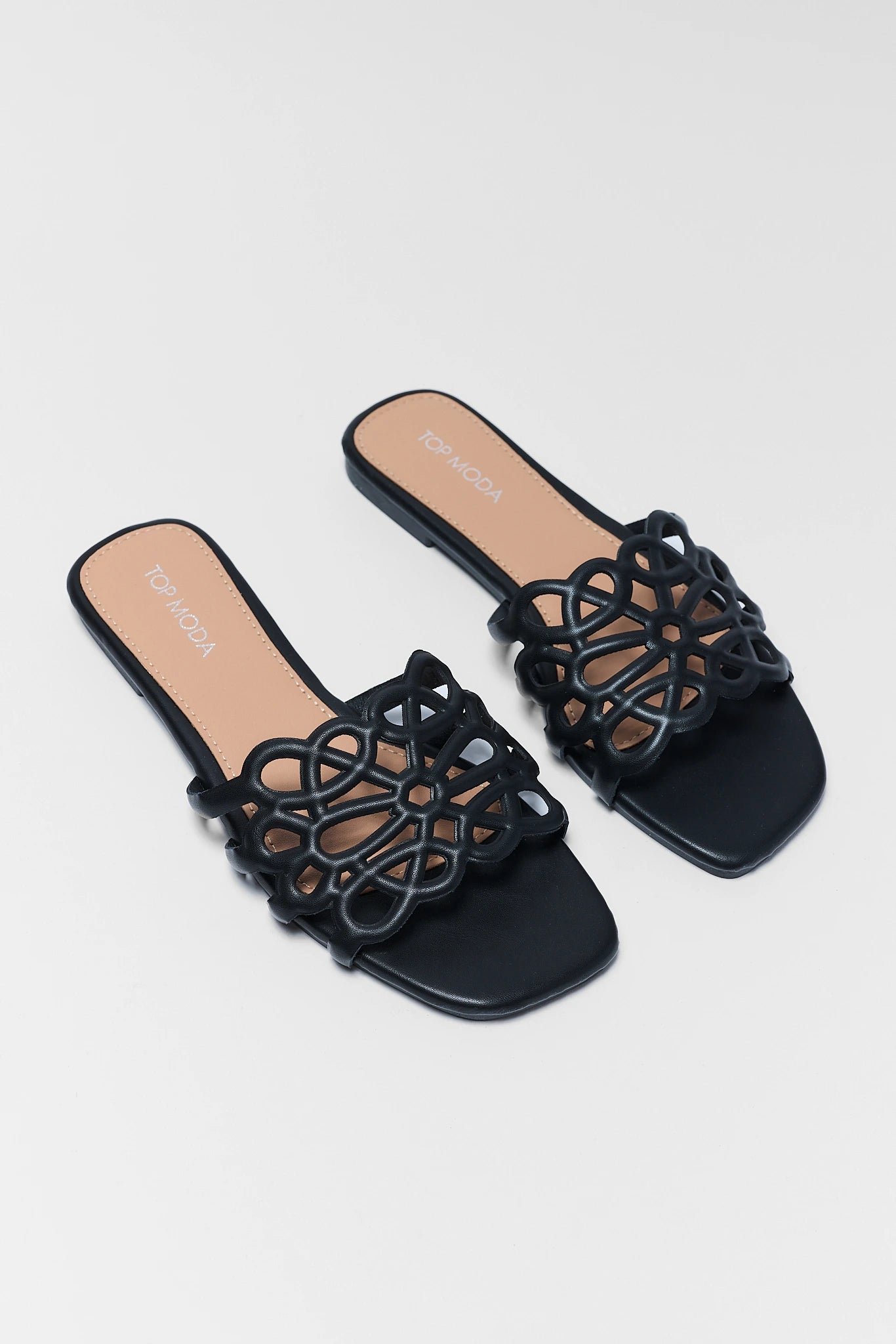 Black sandals with intricate design on a light gray background