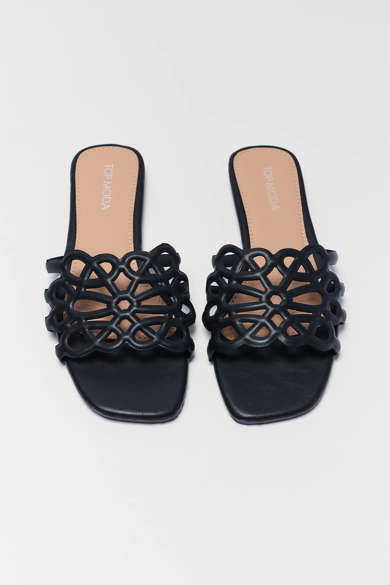 Black sandals with intricate cut-out design on a light gray background