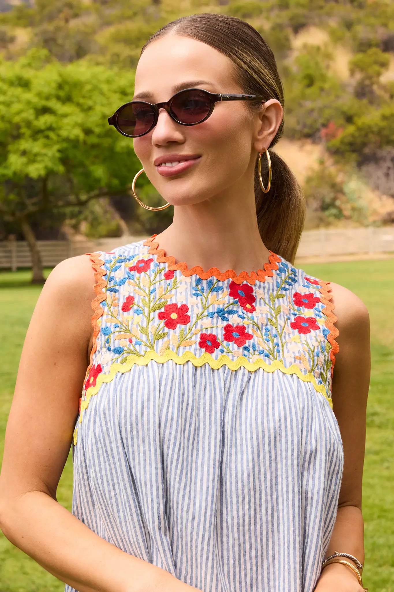 Woman wearing a floral embroidered top with a striped dress outdoors. lifestyle