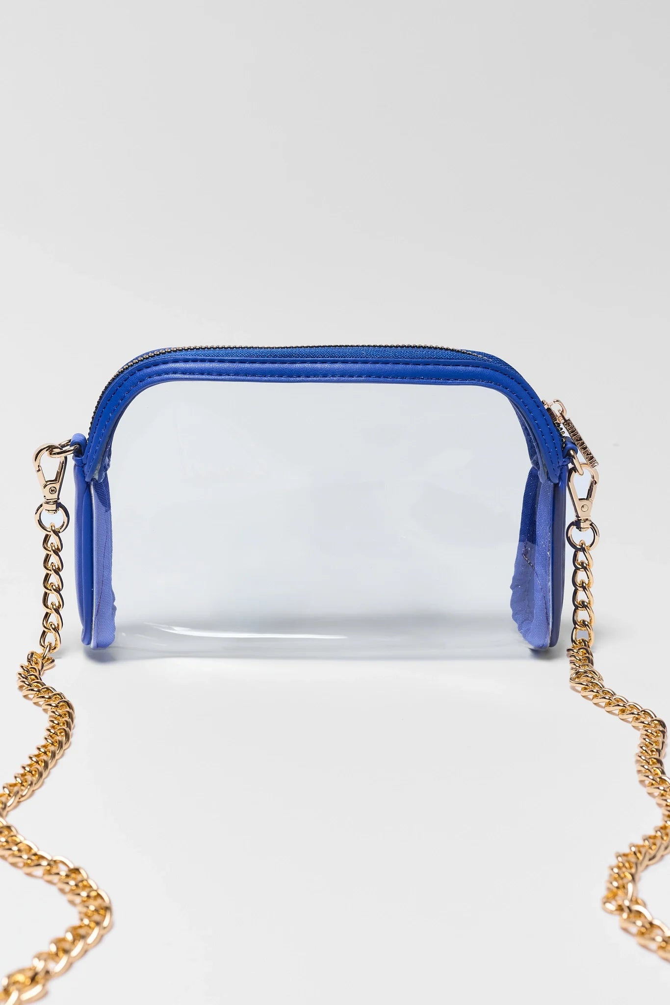 A clear plastic pouch bag with a bright blue zipper and trim, featuring a gold-tone chain strap, photographed on a light gray studio background.
