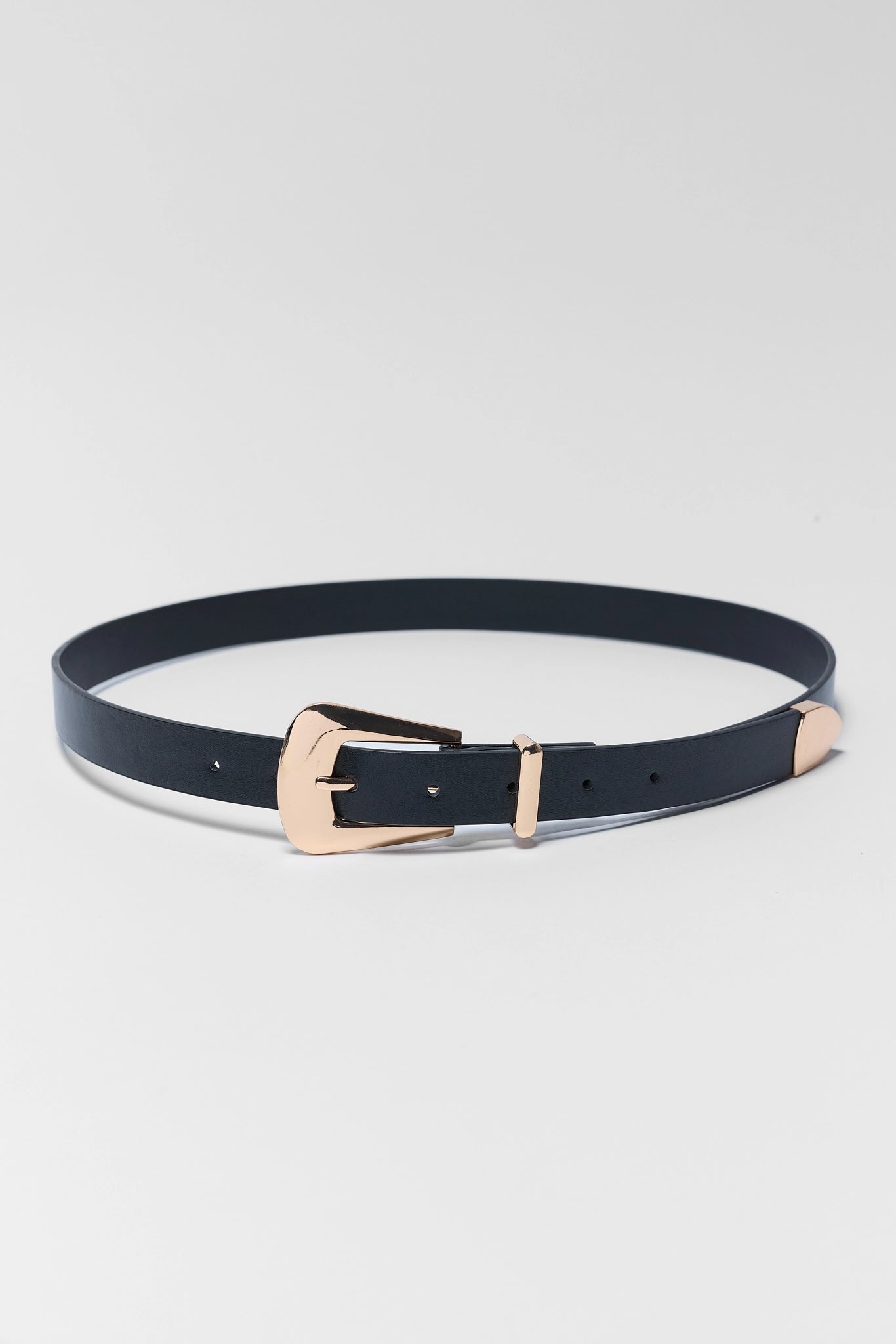 A slim black leather belt with a rose gold buckle, displayed in a circular shape on a light gray background.