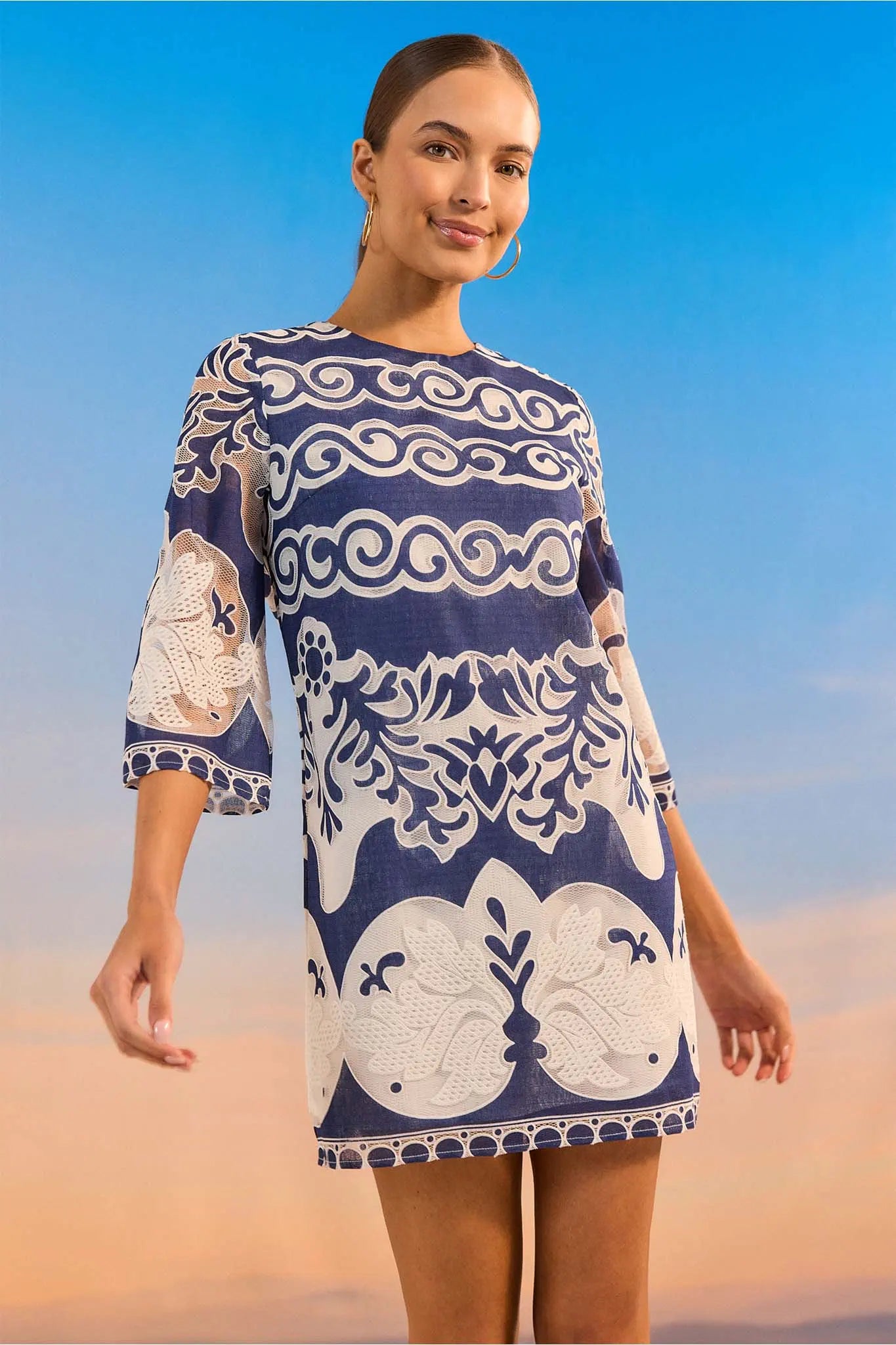 Woman wearing a blue and white patterned dress against a desert background