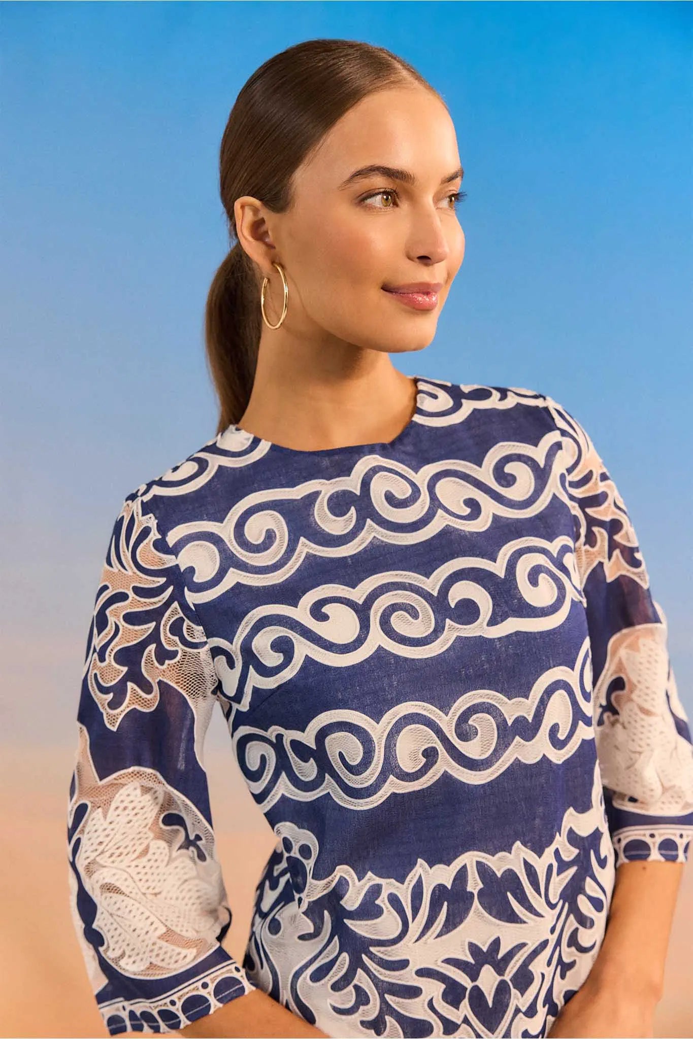 Woman wearing a blue and white patterned top against a blue sky.