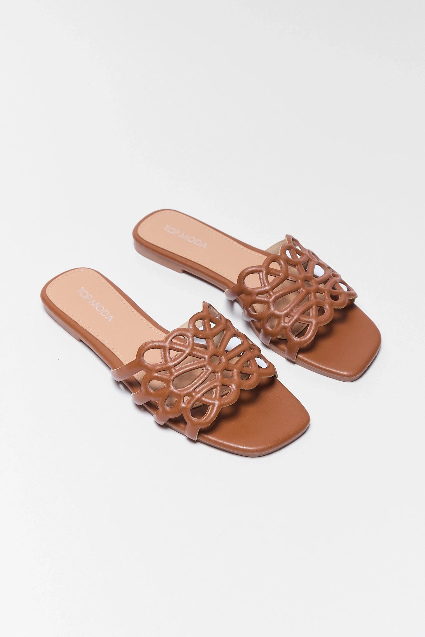 Pair of brown sandals with intricate designs on a light background