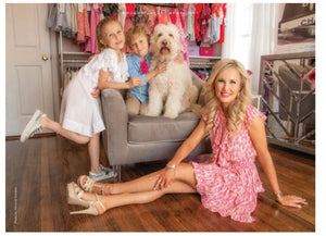 women wearing pink dress and two kids and dog sitting on chair