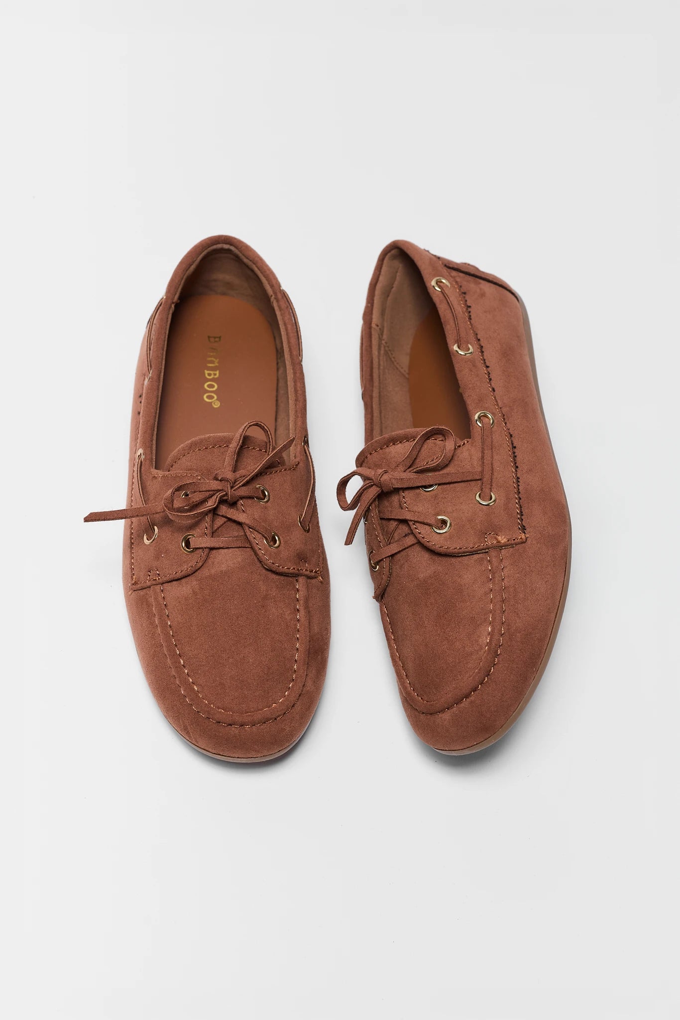Pair of brown suede loafers on a light gray background