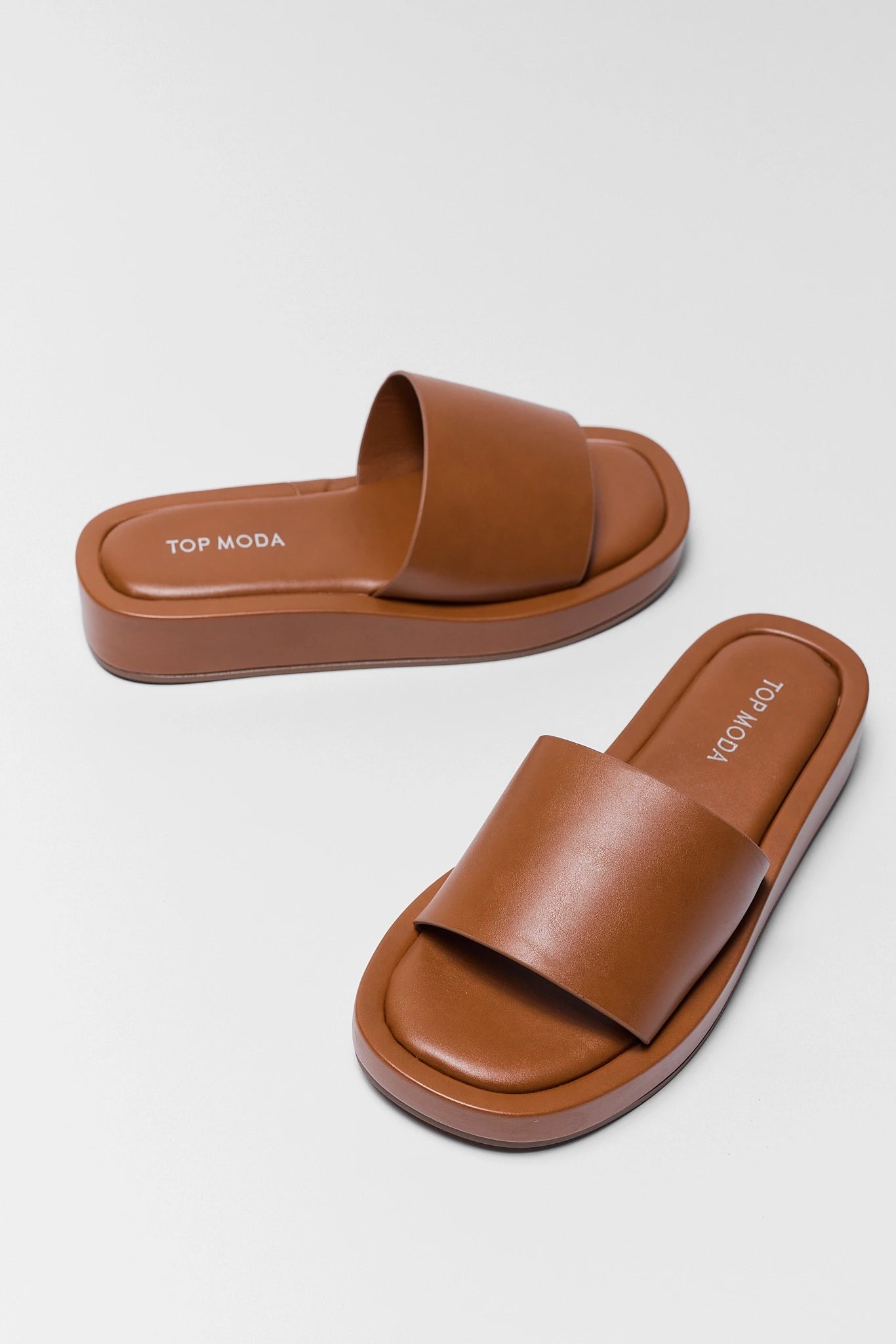Pair of brown sandals with 'Top Moda' branding on a light gray background