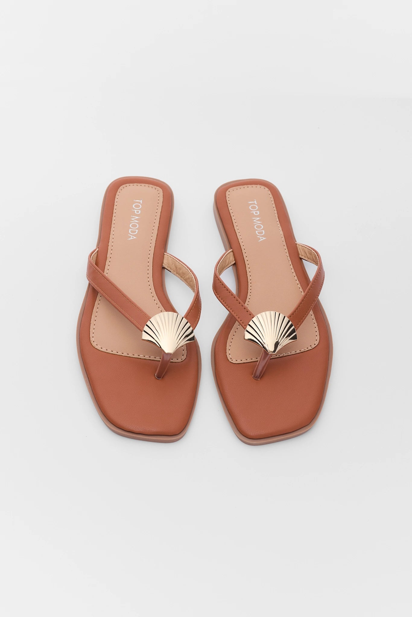 Pair of brown sandals with shell design on a background two