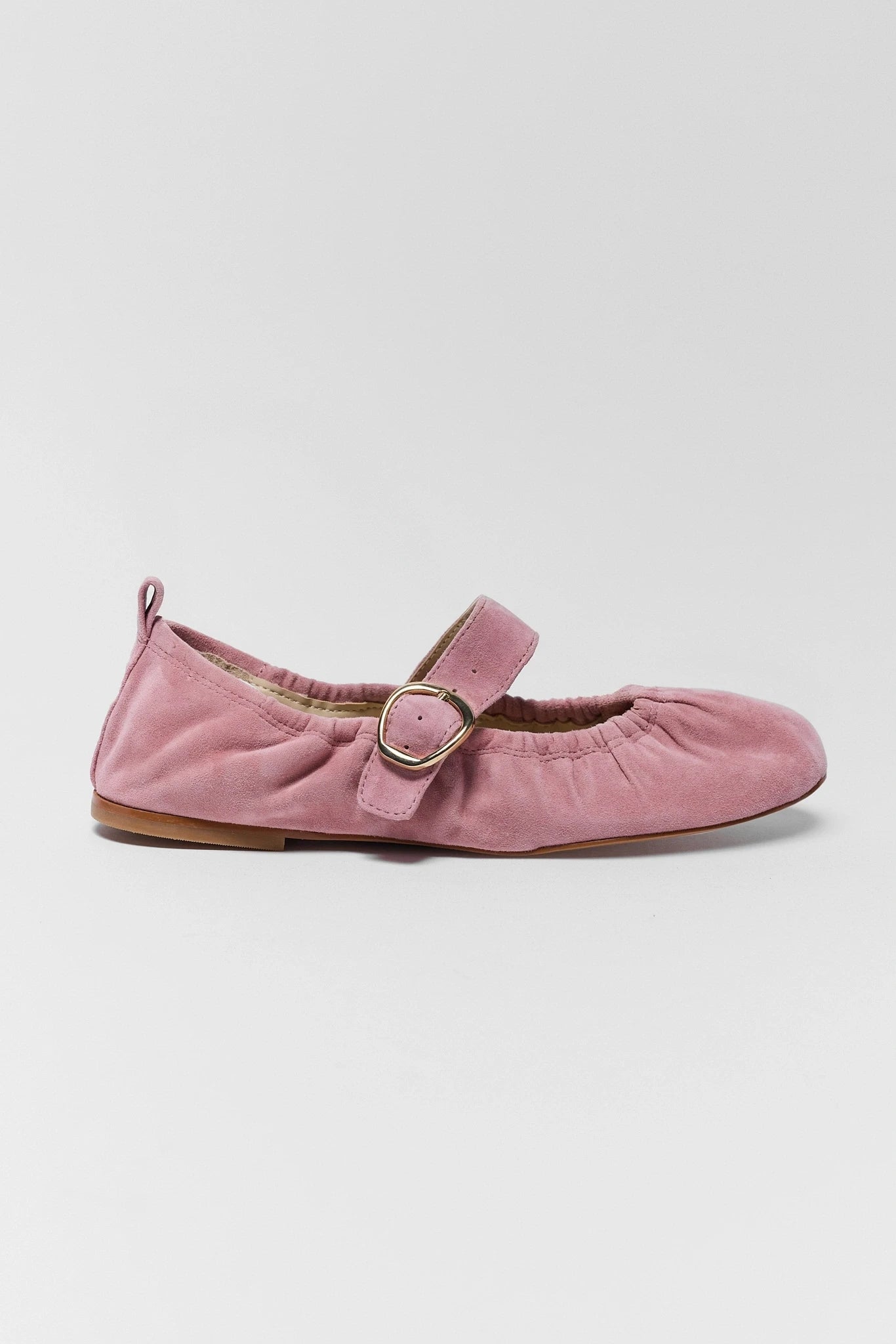 Pink suede shoe with a buckle on a white background