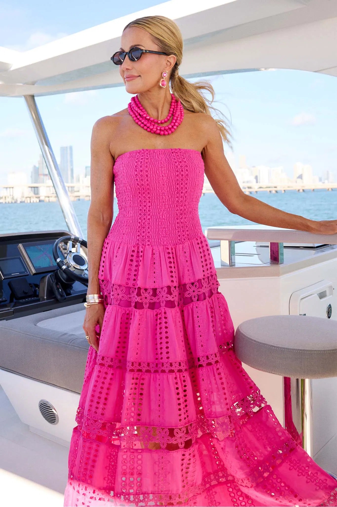 Woman in a pink dress on a boat with a city skyline in the background