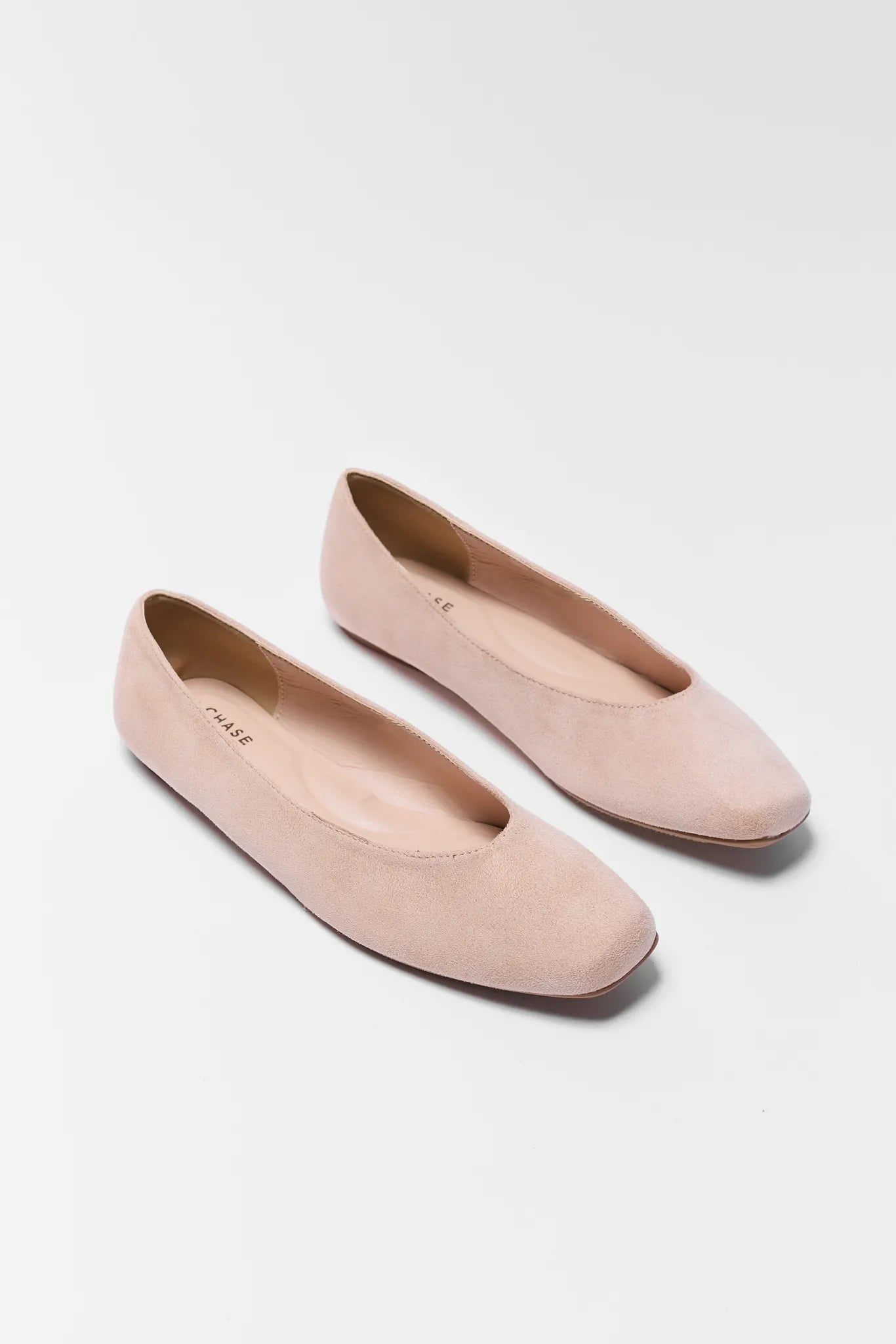 Pair of light pink flats on a white background