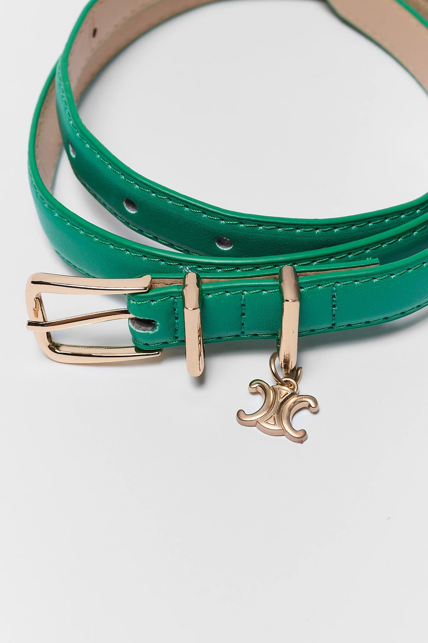A green leather belt with a gold-tone buckle and a dangling Celine logo charm, shown on a clean white background.