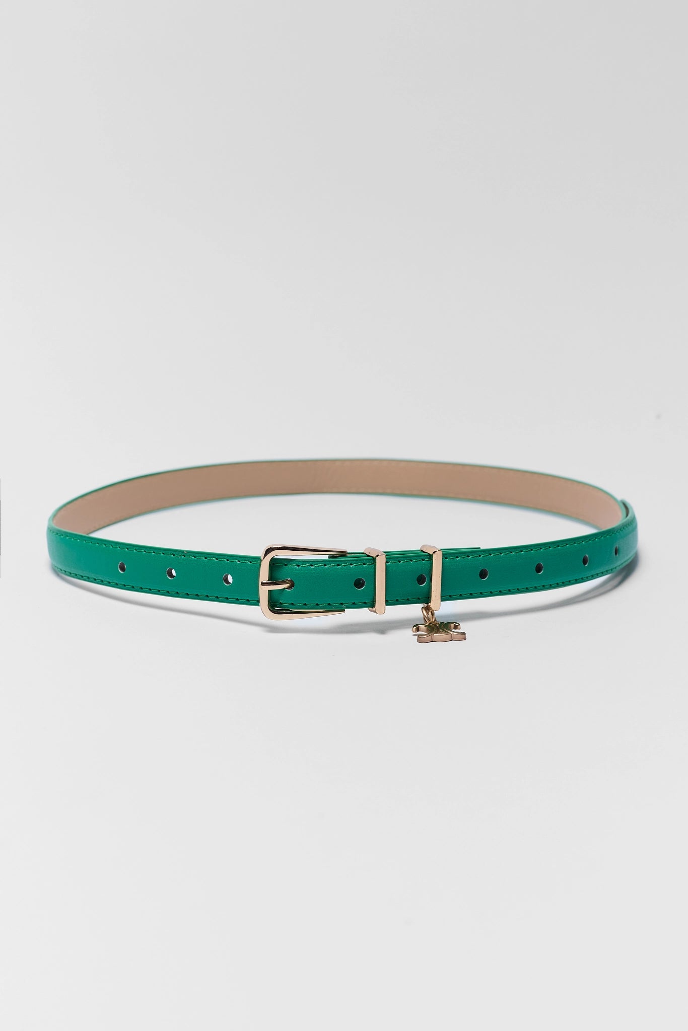 A slim green leather belt with a gold-tone buckle and a small hanging charm, displayed on a light gray background.