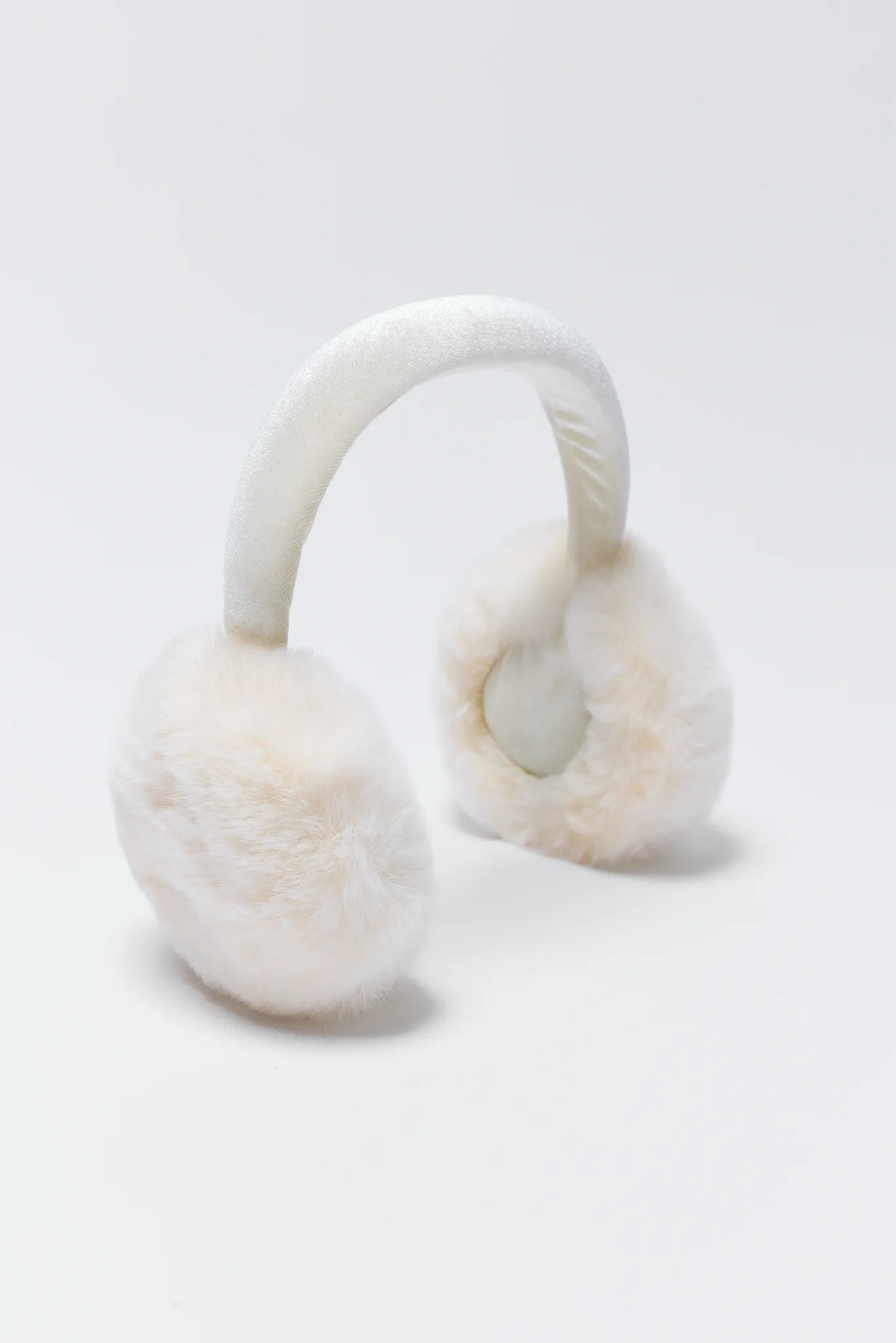 White furry ear muffs on a light gray background