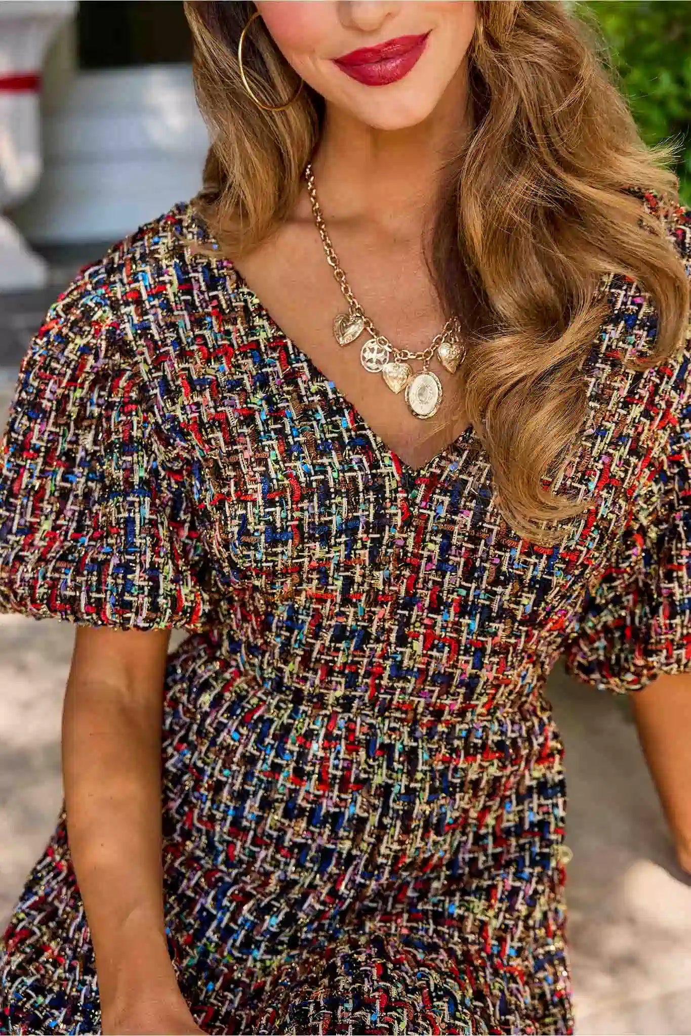 Woman in a patterned cindy dress standing in front of a decorated door with wreaths and bows.