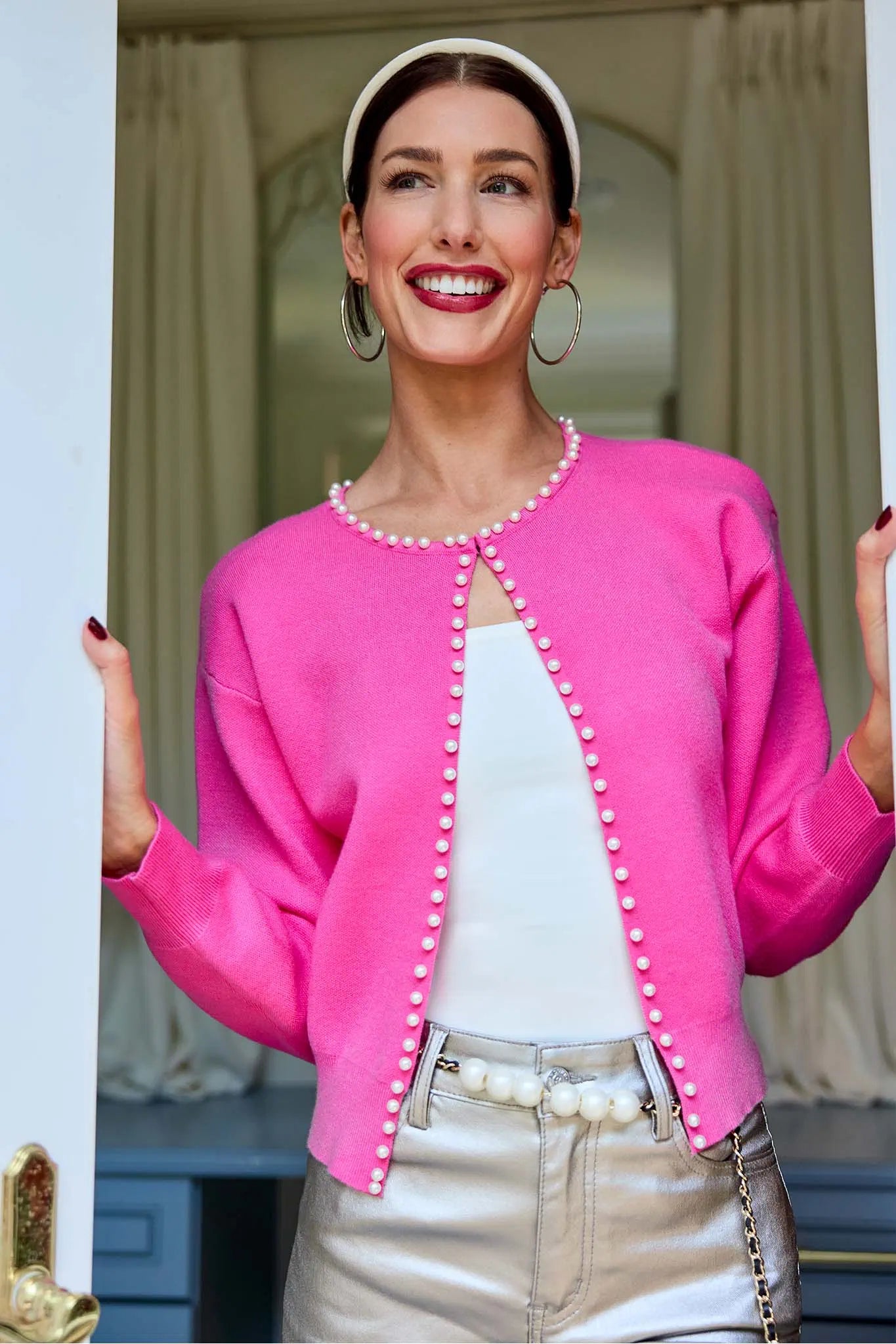 Woman wearing a pink cardigan with pearl buttons indoors