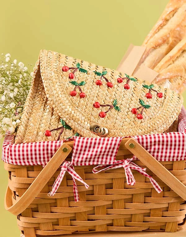 Woven picnic basket with a straw handbag featuring cherry design on a green background