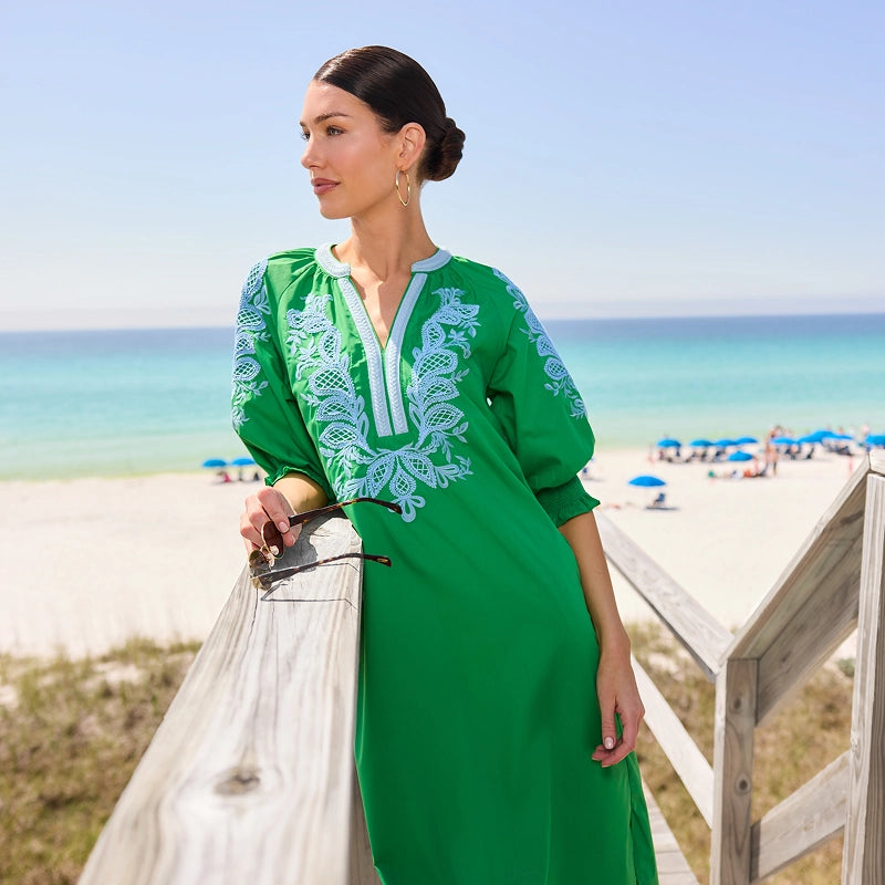 Woman in a green dress with white embroidery on a beach collection