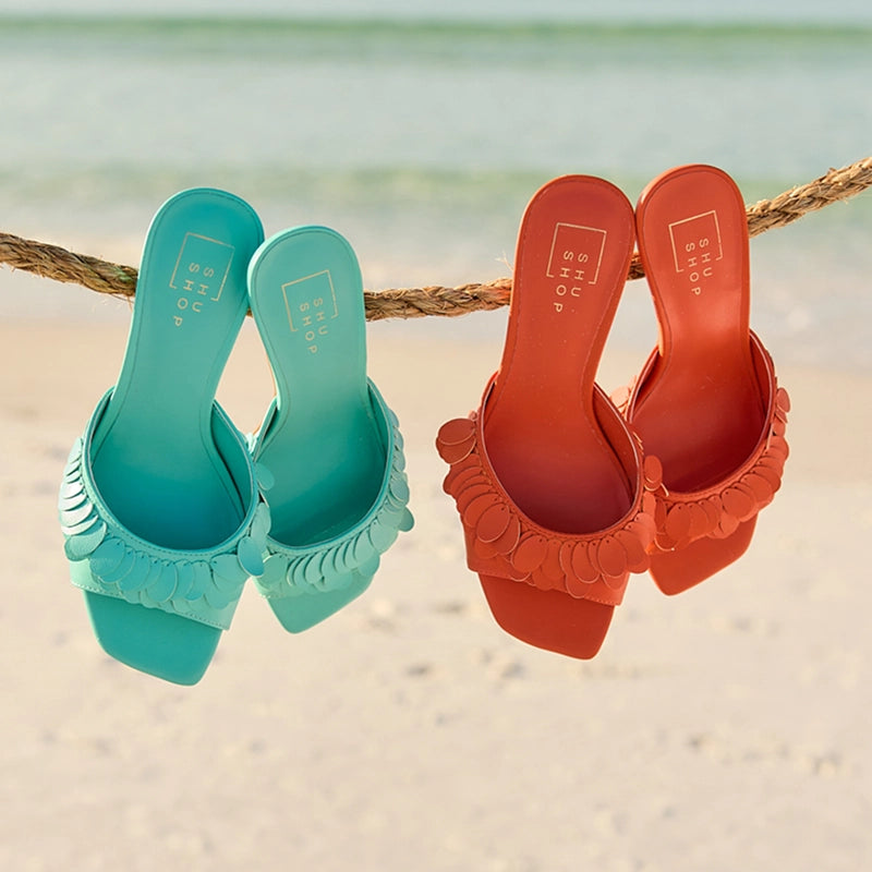 Turquoise and orange sandals hanging on a rope with a beach background collection