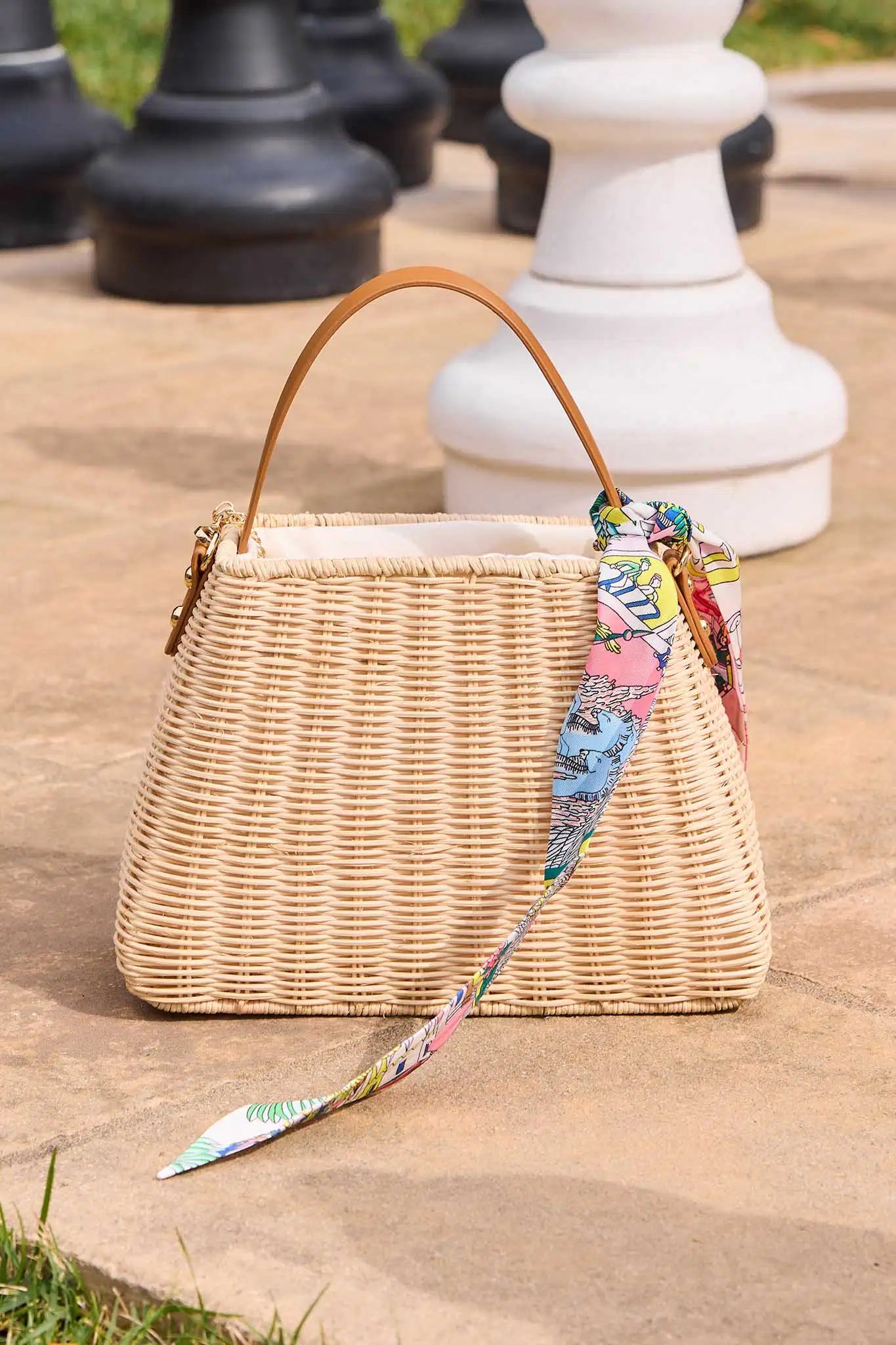 Wicker handbag with a colorful strap on a stone surface