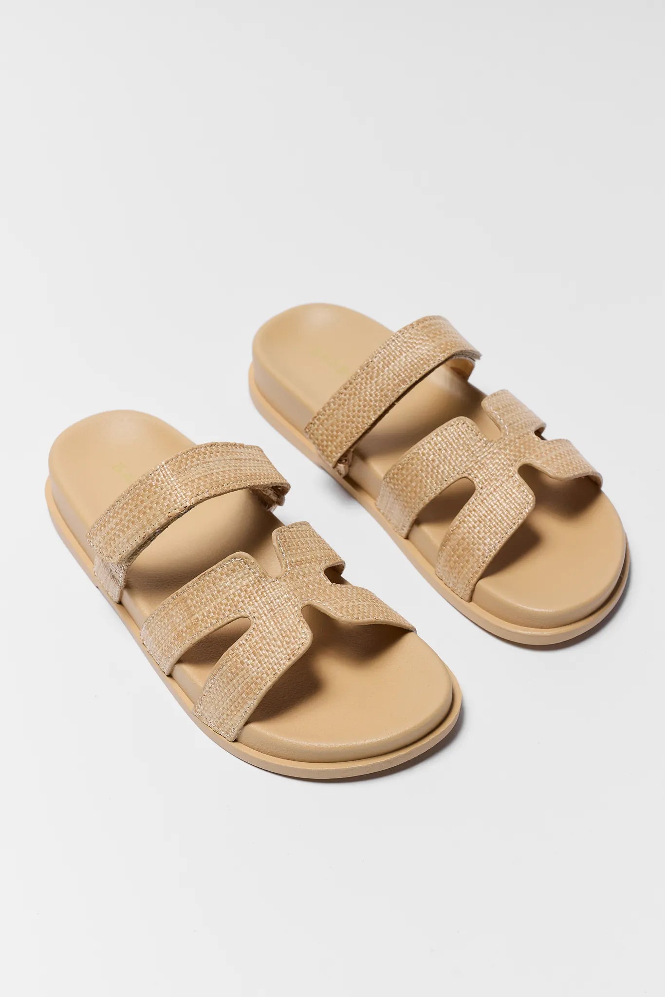 Pair of beige sandals with multiple straps on a light gray background