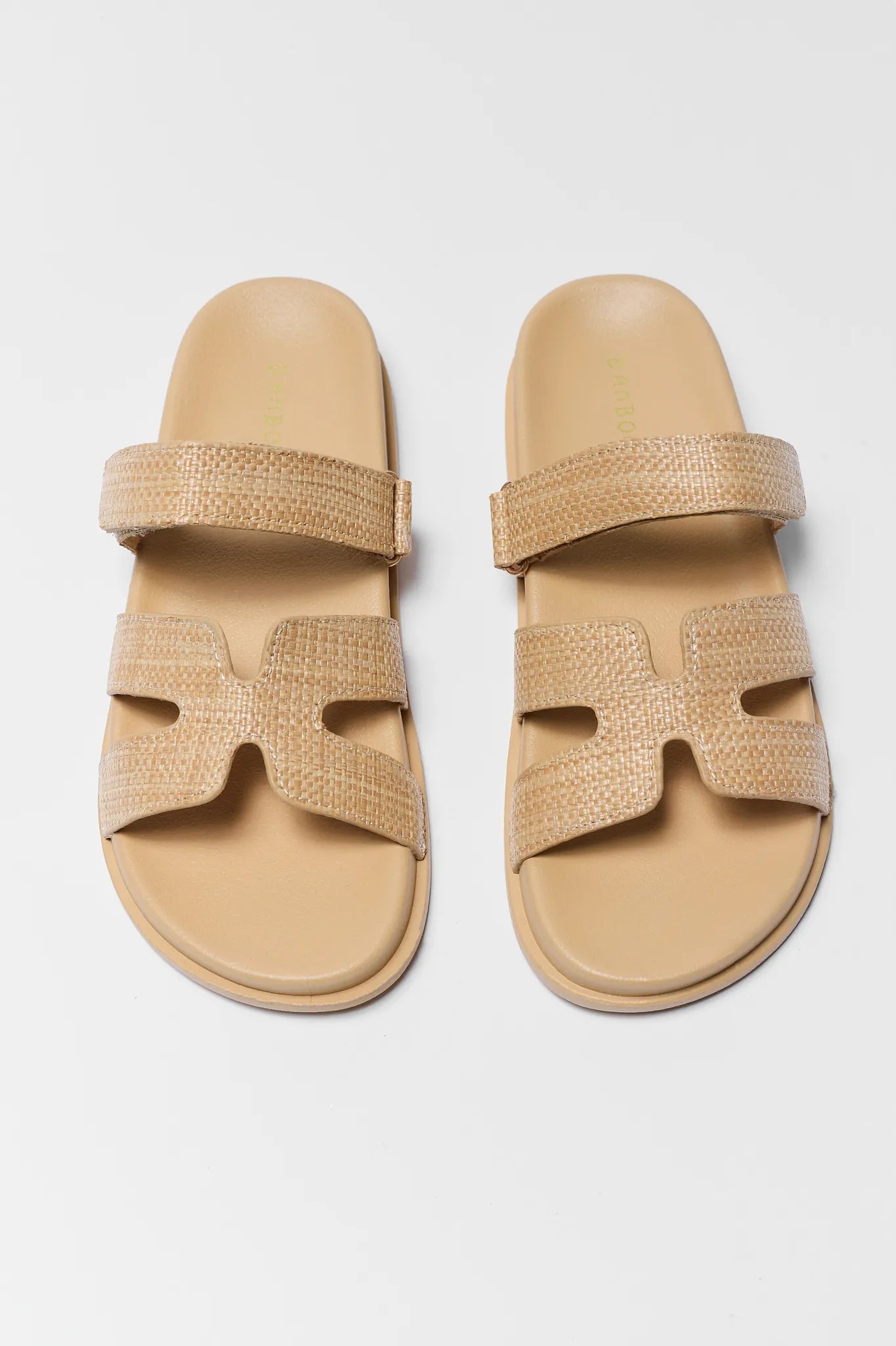 Pair of beige sandals with woven straps on a light gray background