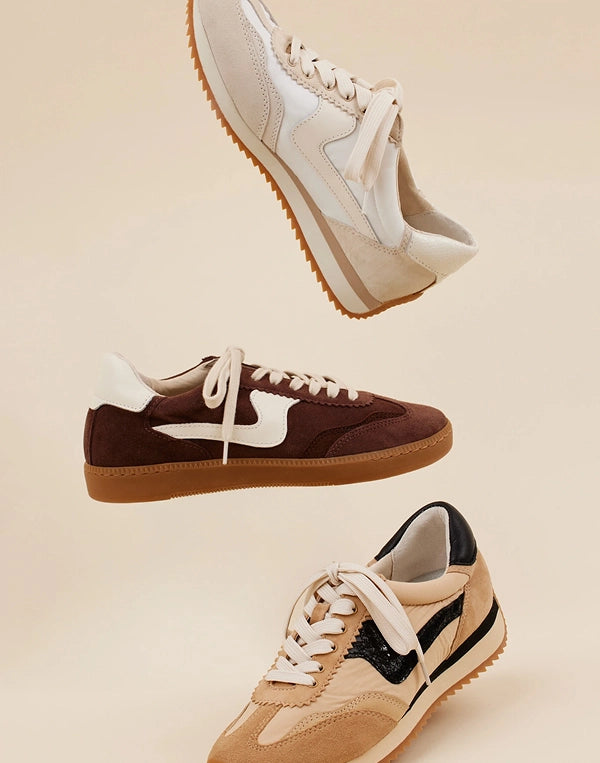 Three pairs of dolce vita sneakers in different colors on a beige background