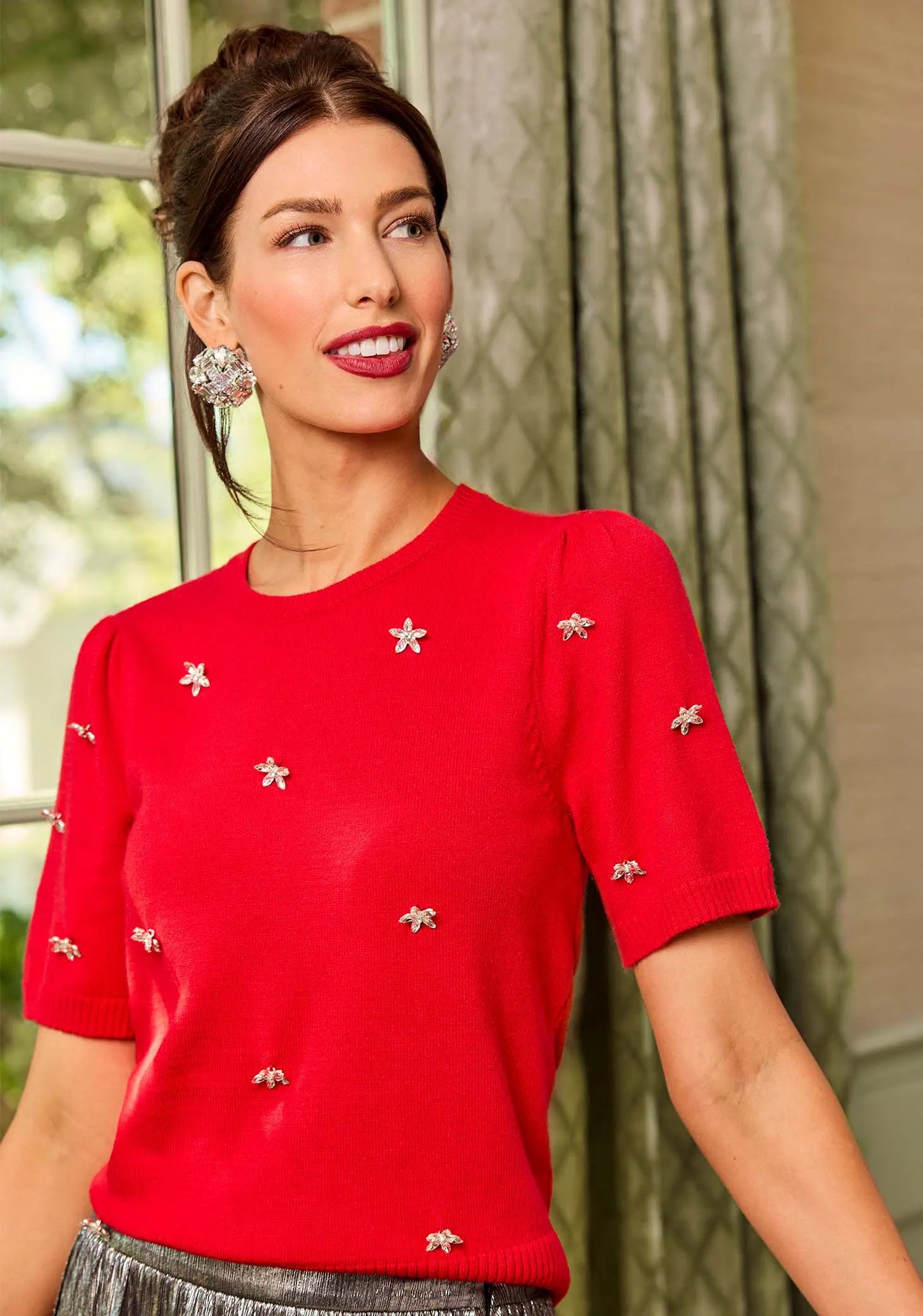 Woman wearing a red sweater with decorative elements indoors