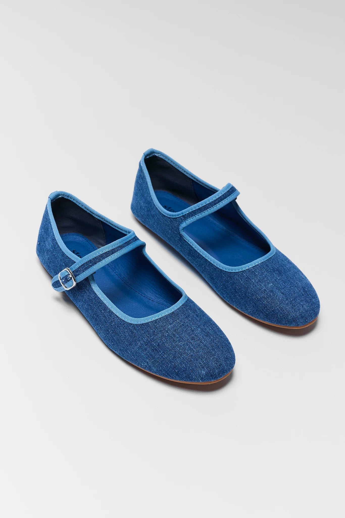 two ellie blue denim flats on white background