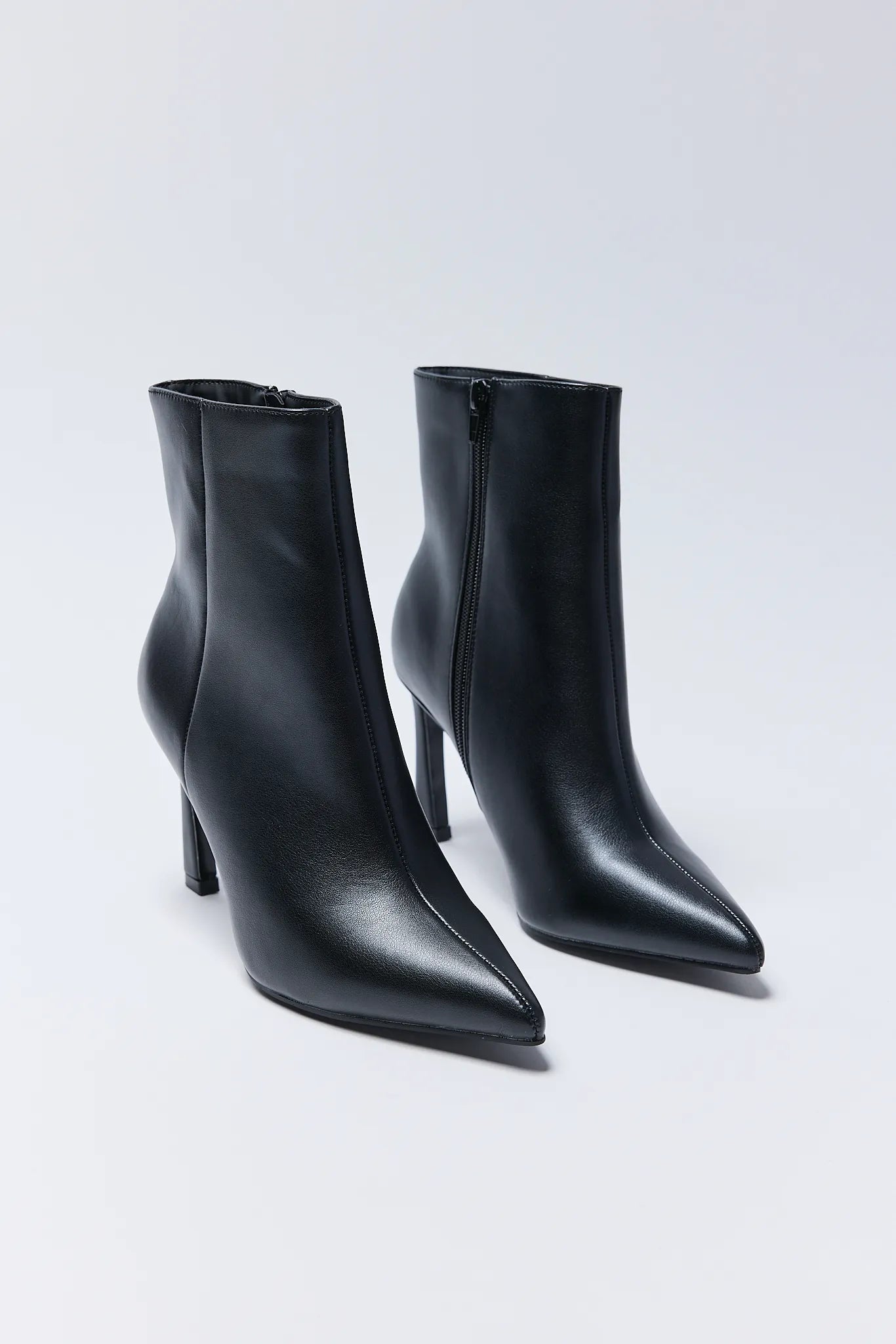 Pair of black high-heeled ankle Emery Boots on a light gray background